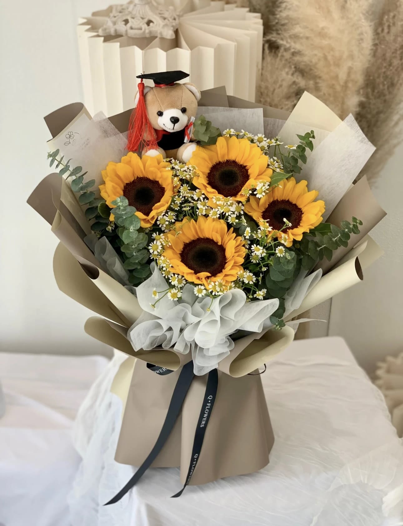Bouquet of sunflowers with a teddy bear wearing a graduation cap