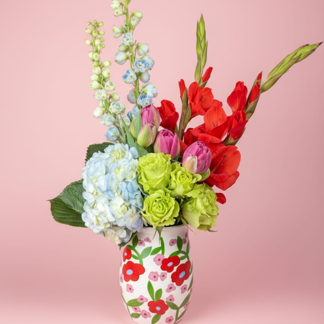 Colorful bouquet in a painted vase with hydrangeas, tulips, and red gladiolus