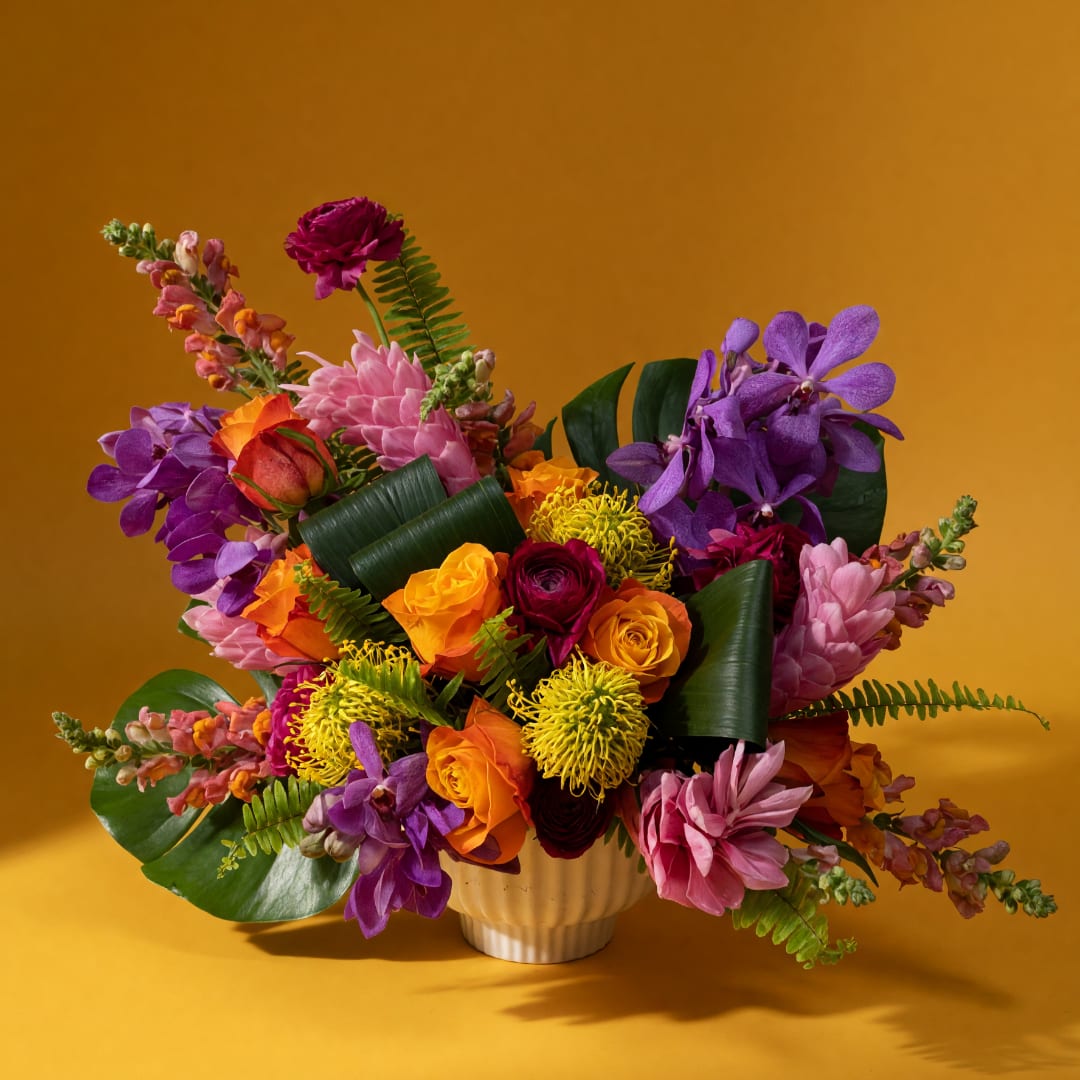 Colorful bouquet of roses, orchids, and mums in a white vase