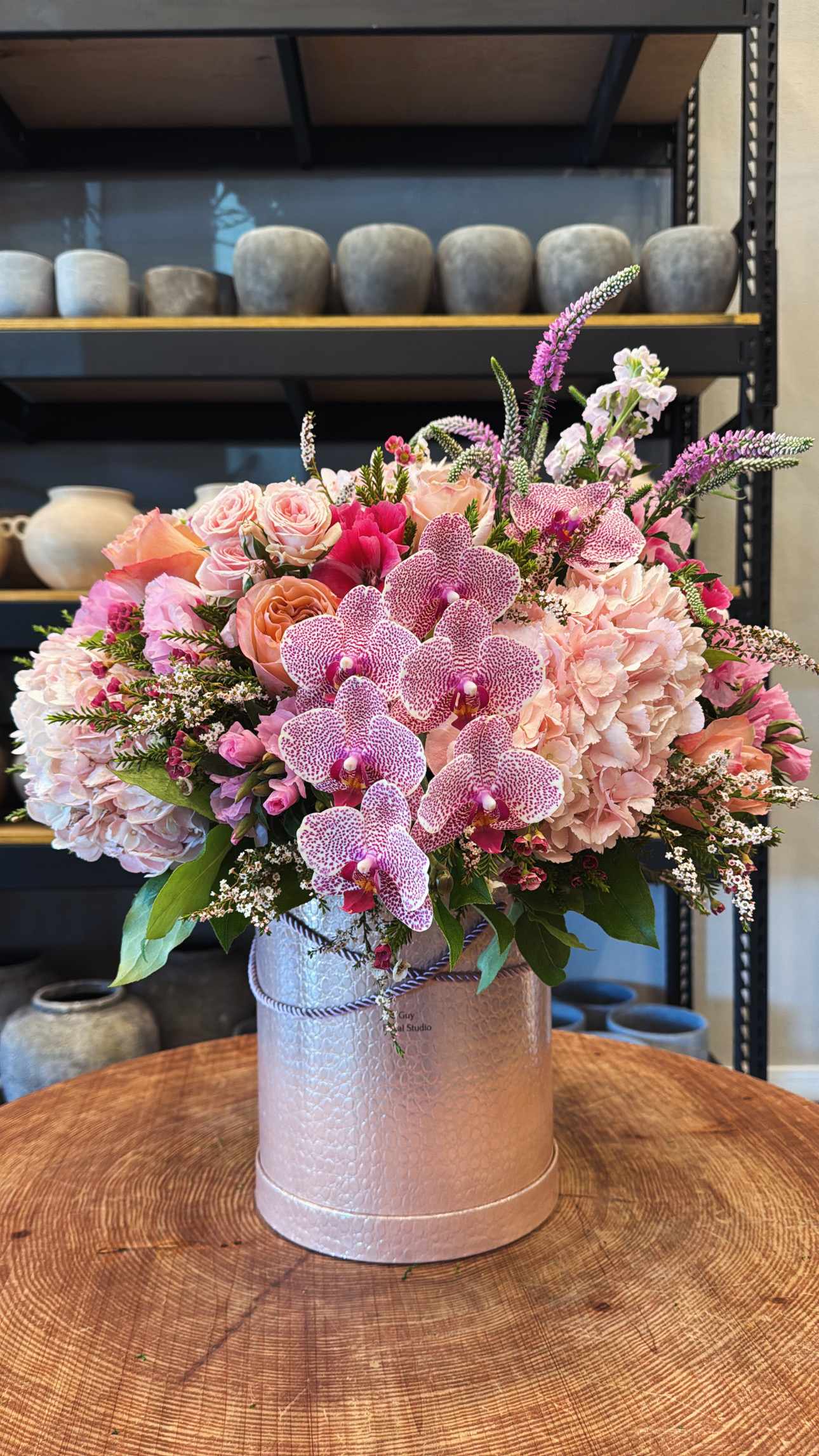 Pink orchid and rose arrangement in a silver hatbox