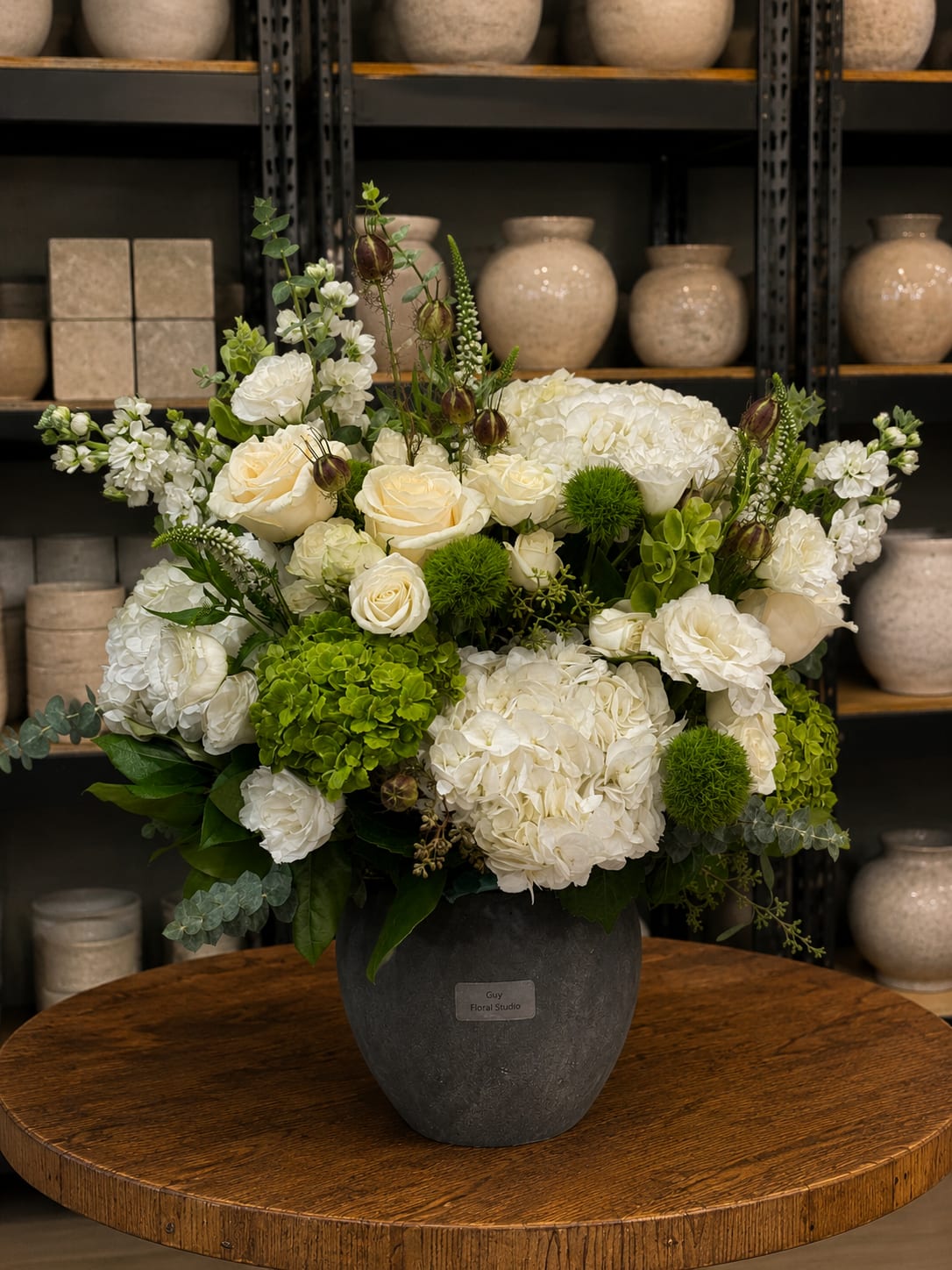 White floral arrangement in a dark vase with green accents