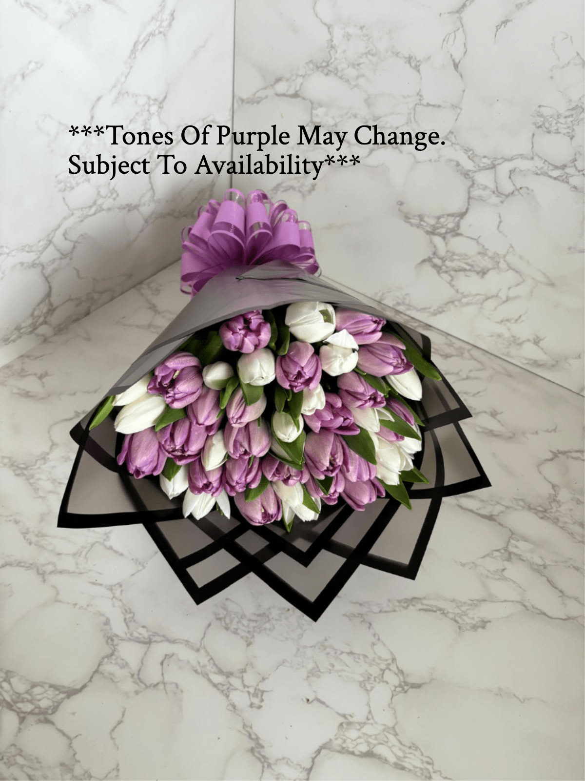 Bouquet of purple and white tulips wrapped in black paper with a purple bow