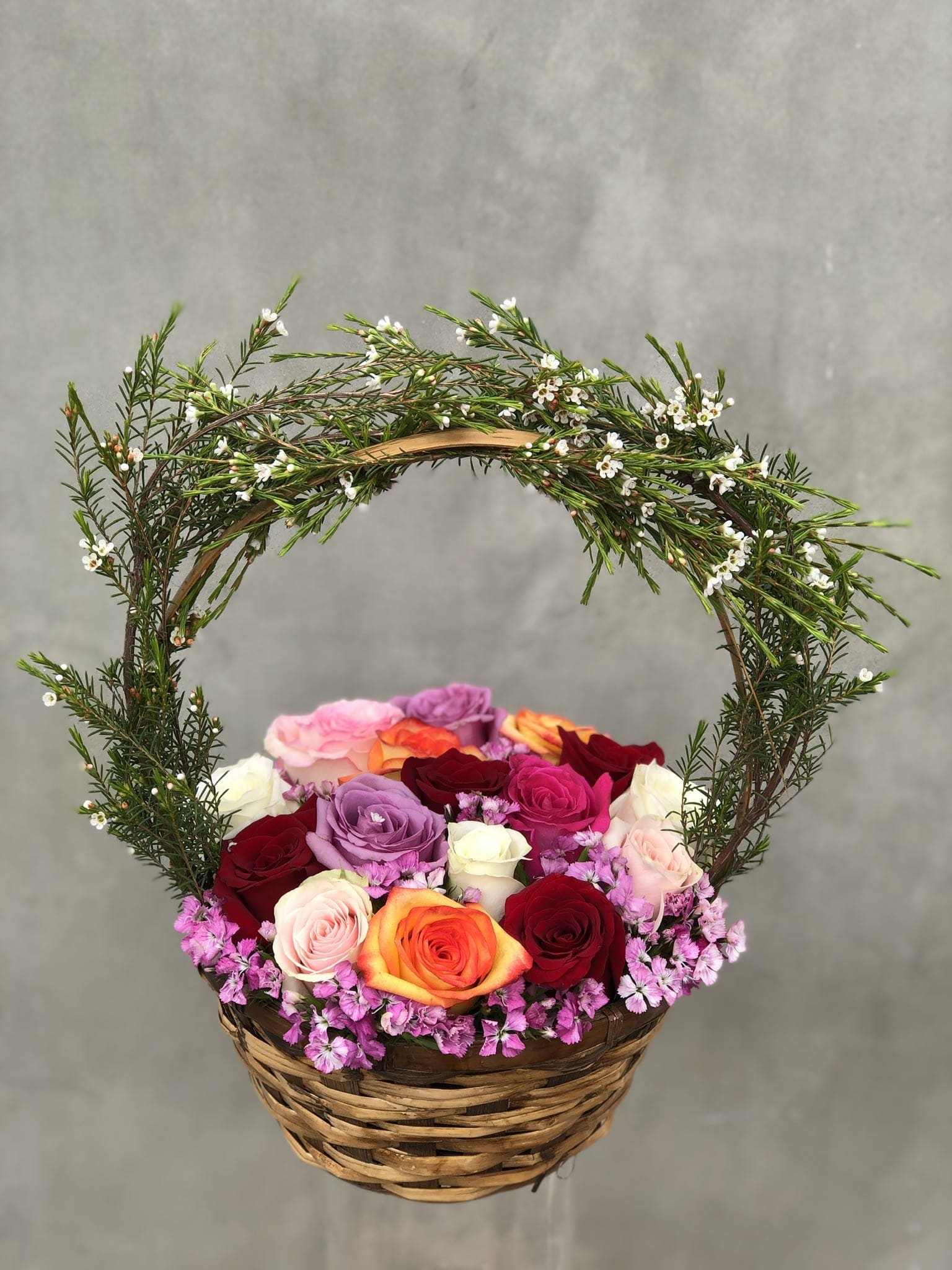 Basket of multicolored roses with a curved floral handle