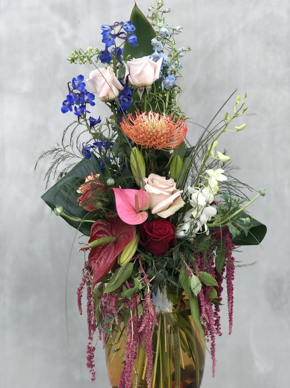 Tall mixed bouquet with roses, orchids, and anthuriums in a vase