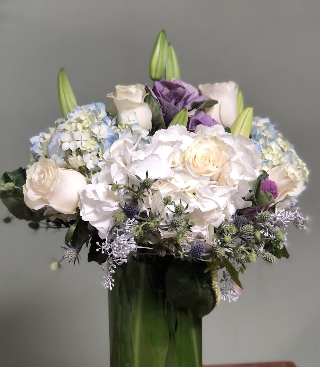 Bouquet of white and lavender flowers in a tall glass vase