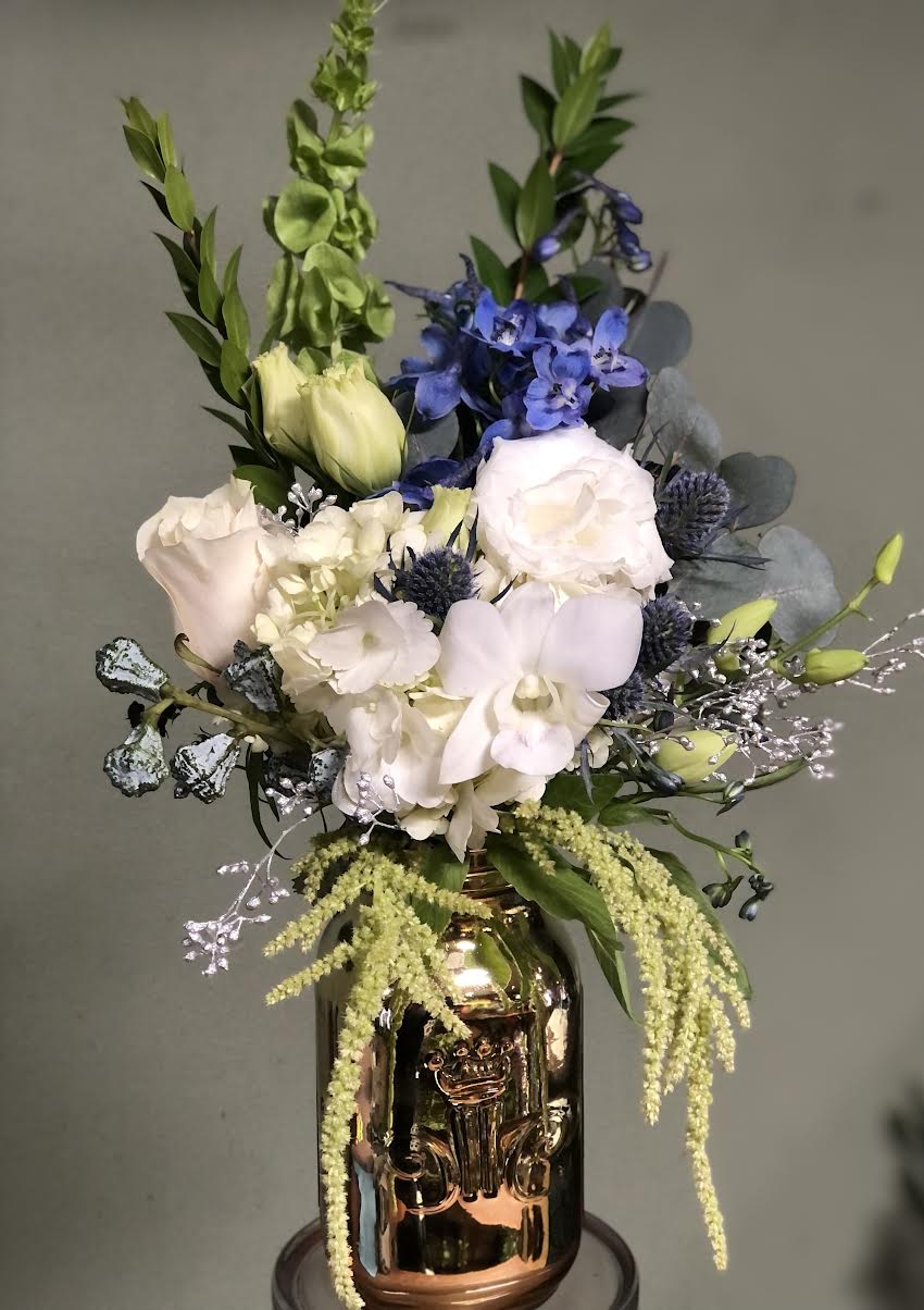 Mixed bouquet in a metallic vase with white, blue, and green flowers