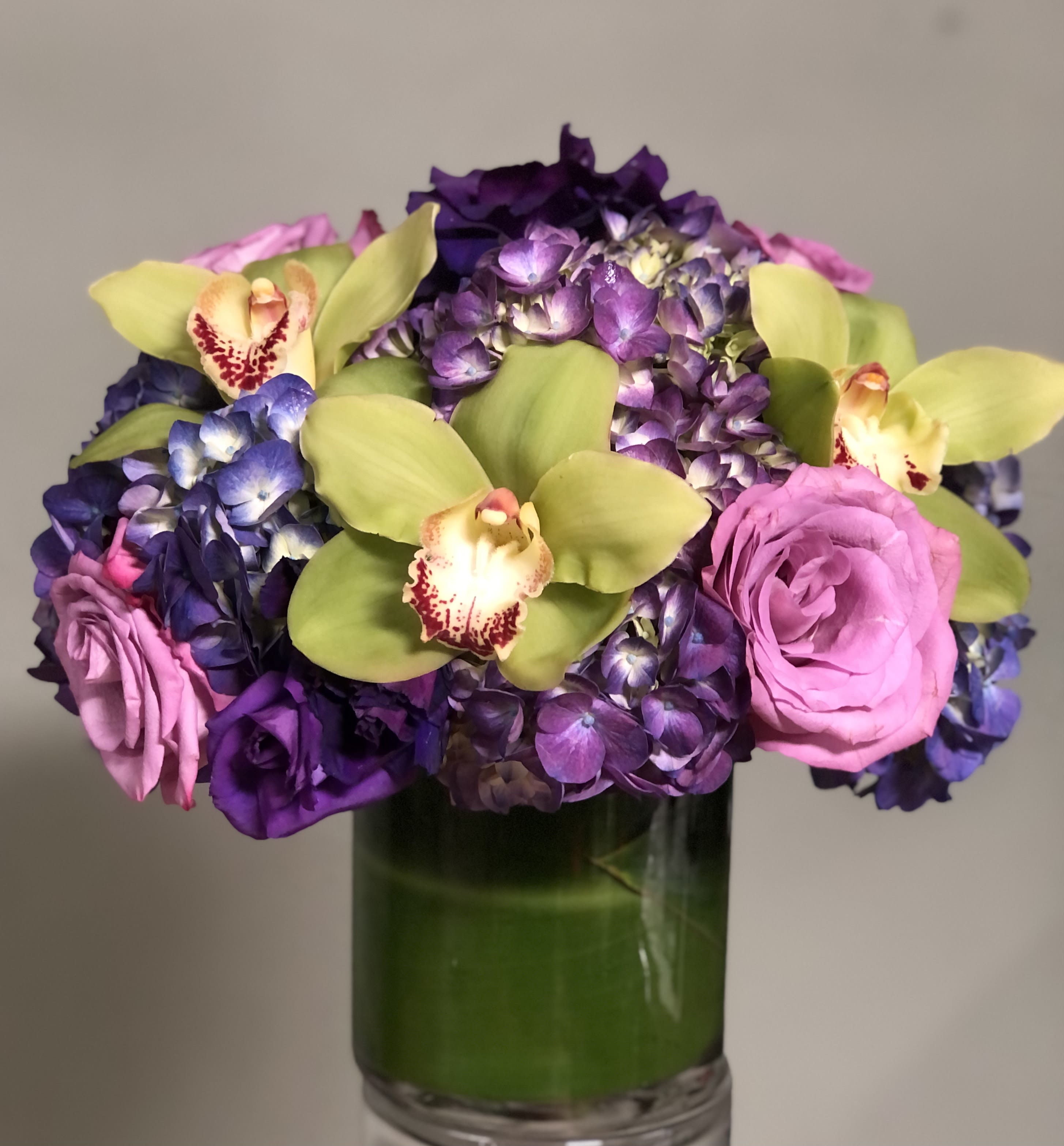 Magical Orchids - Green Cymbidium orchids, Purple Hydrangeas, Lisianthus and roses in vase.
