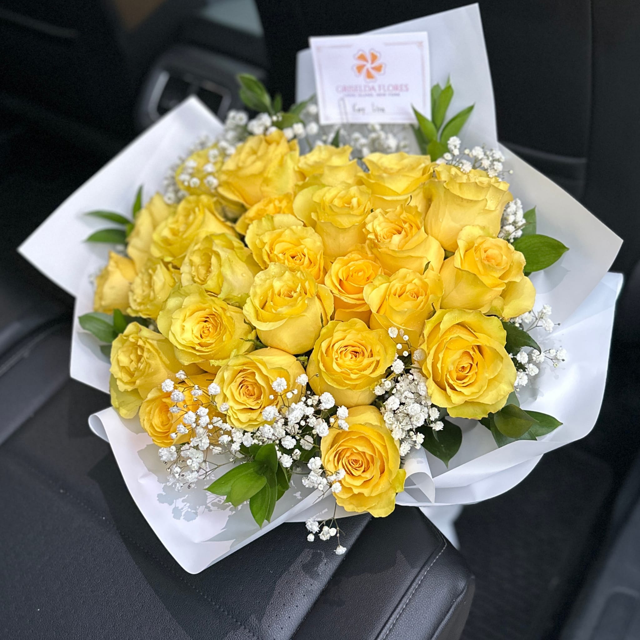 Bouquet of yellow roses with white baby's breath in white wrapping
