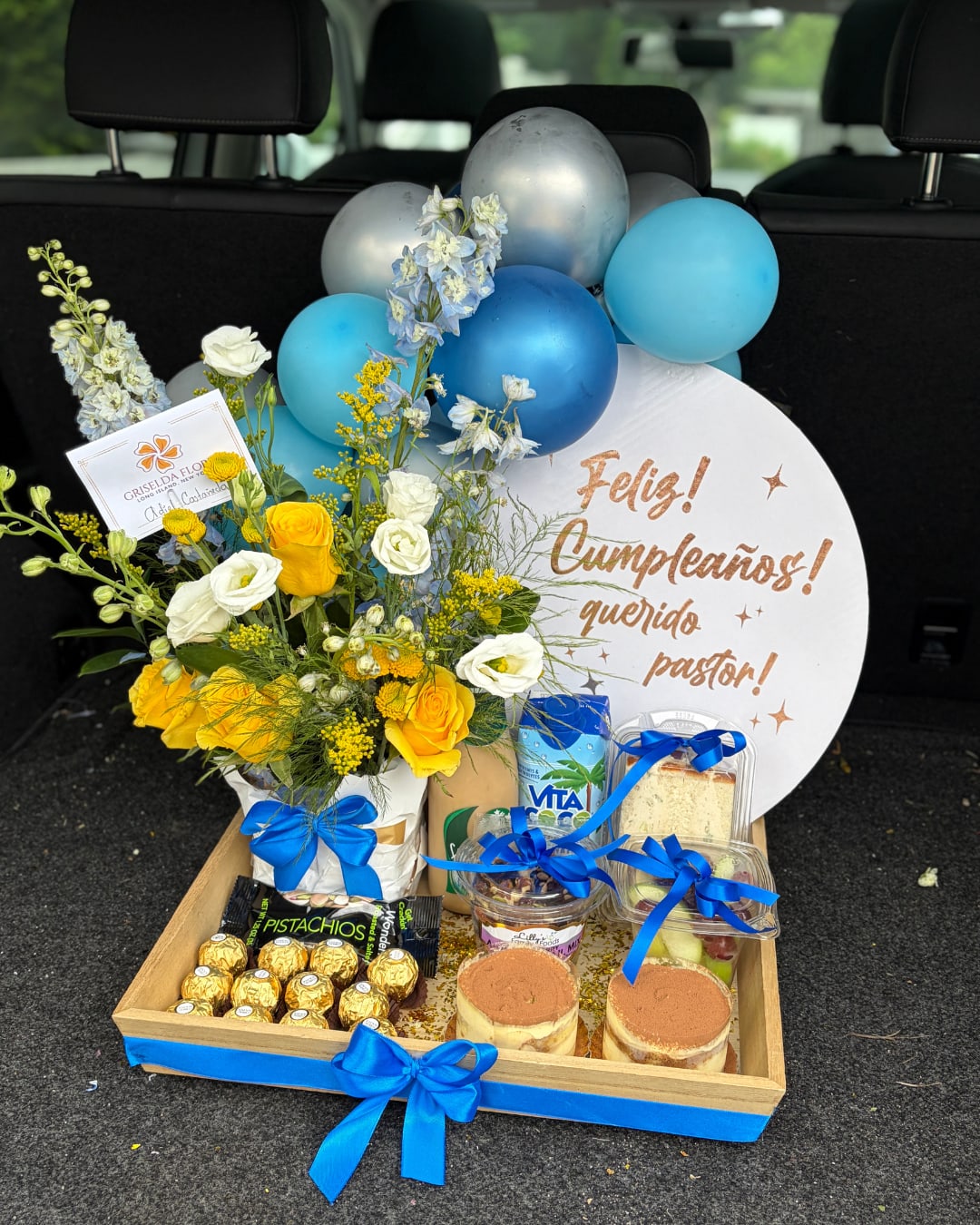 Bandeja sorpresa para caballeros en Long Island New York - Esta bandeja incluye: - Bandeja de madera - Globos - Texto personalizado - Arreglo con flores - Cajita mixta de galletas o tiramisu. - Chocolates - Frutas - Cafe helado - Agua de coco - Sandwich - Frutos secos