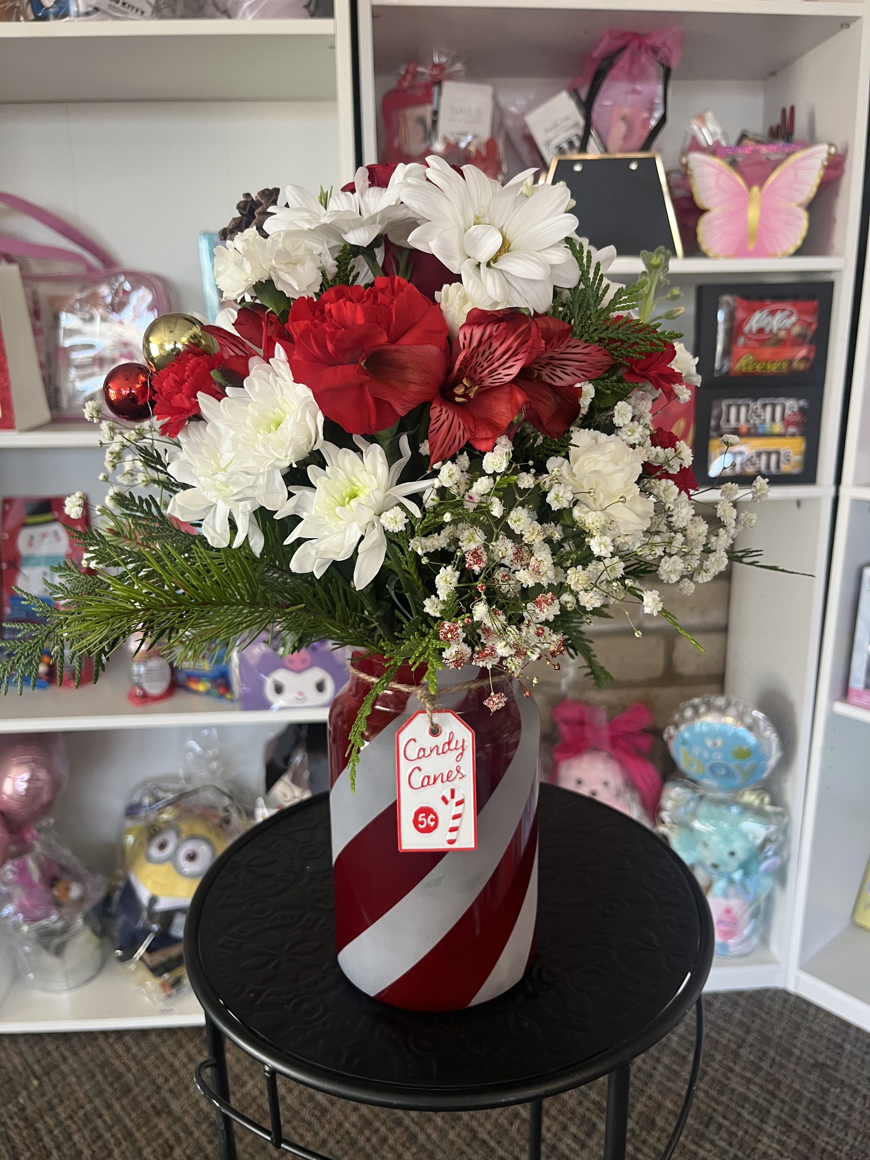 Red and white floral arrangement in a candy cane vase
