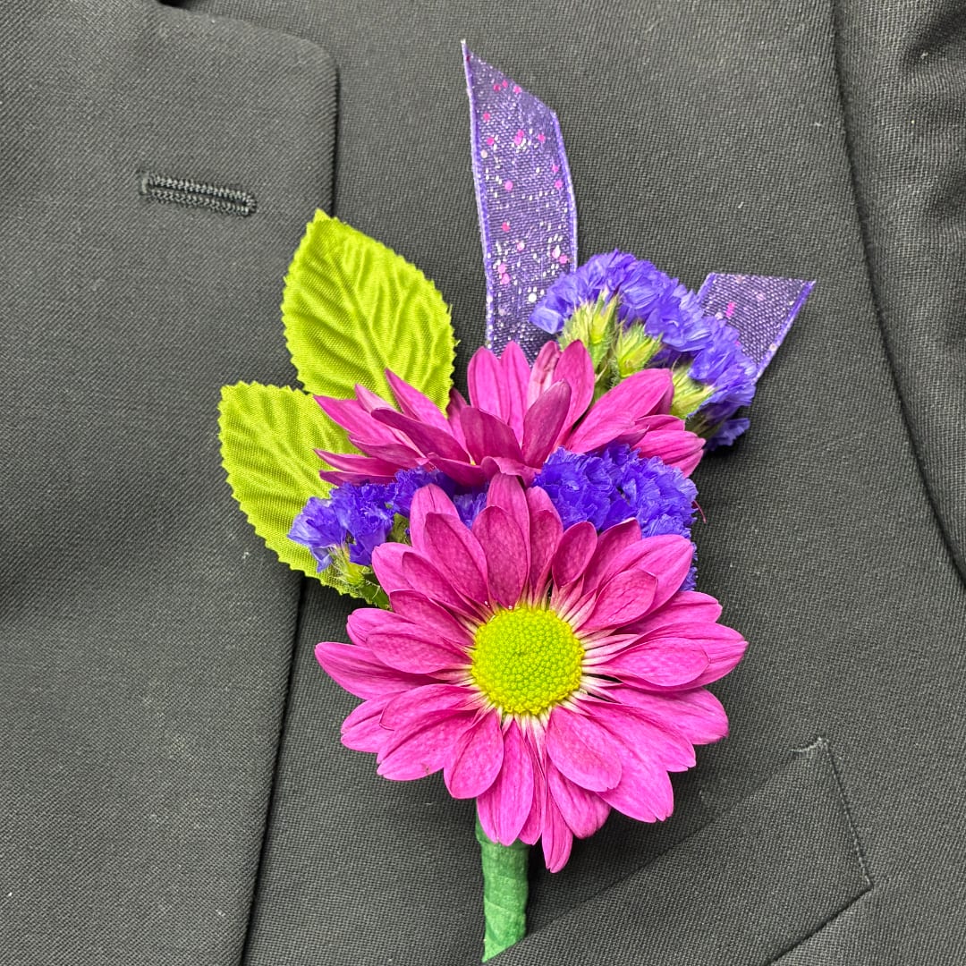 Pink daisy boutonniere with purple accents pinned to a dark suit jacket