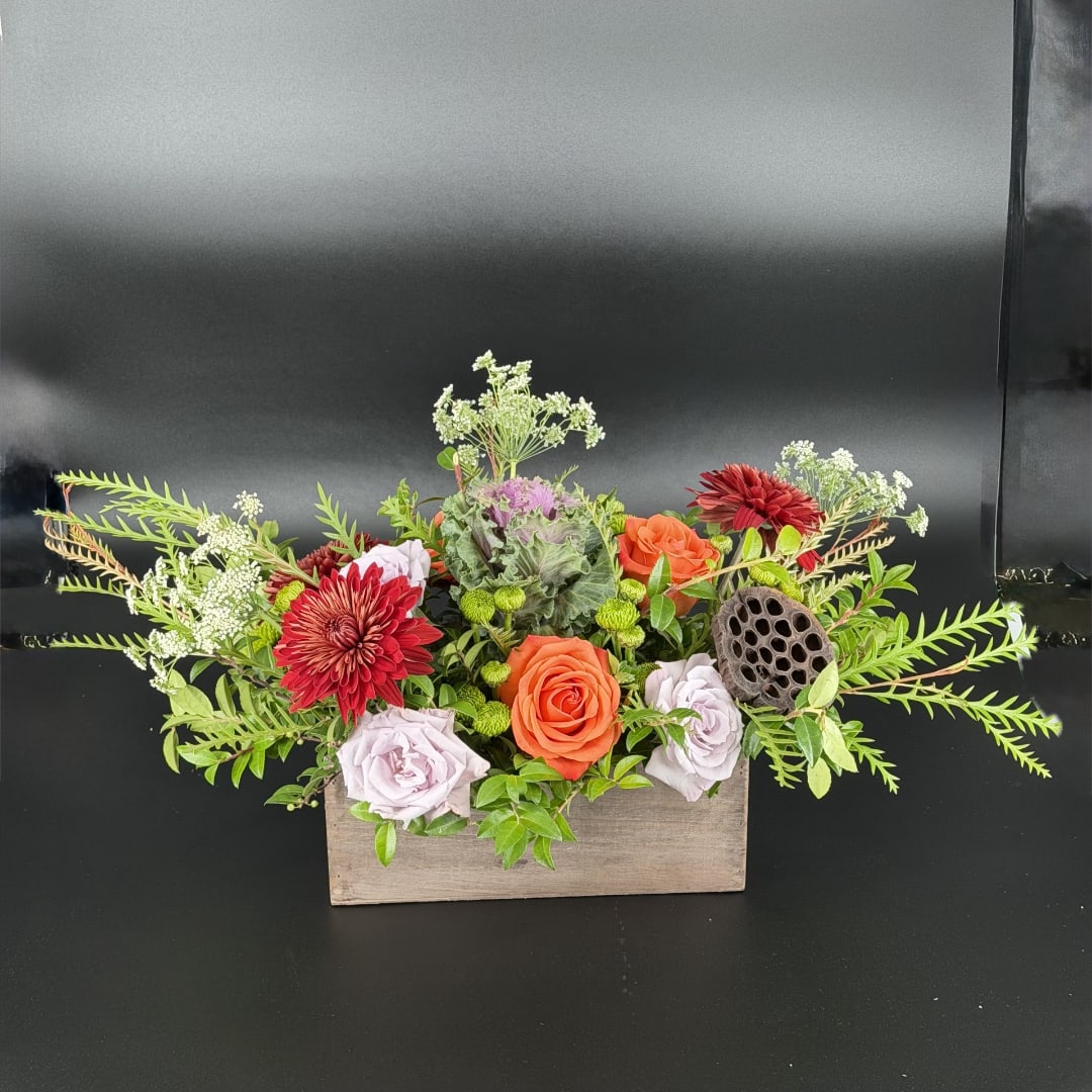 Mixed flower arrangement in a wooden box with orange and lavender roses