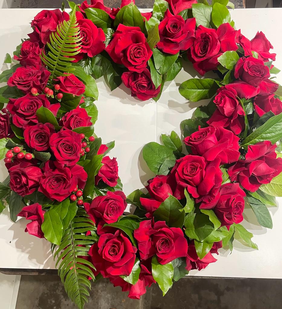 Heart-shaped arrangement of red roses with green foliage