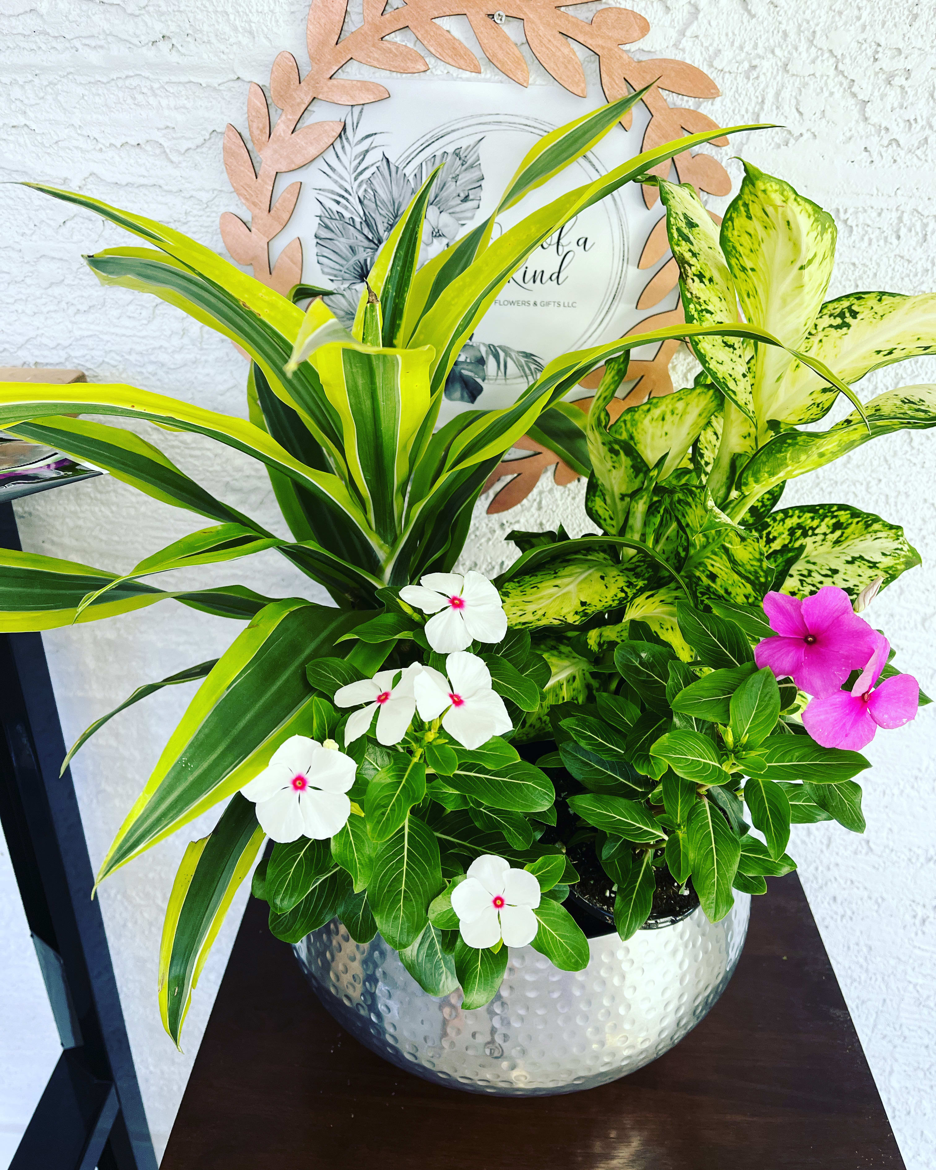 Potted tropical plant arrangement with white and pink flowers in a silver bowl