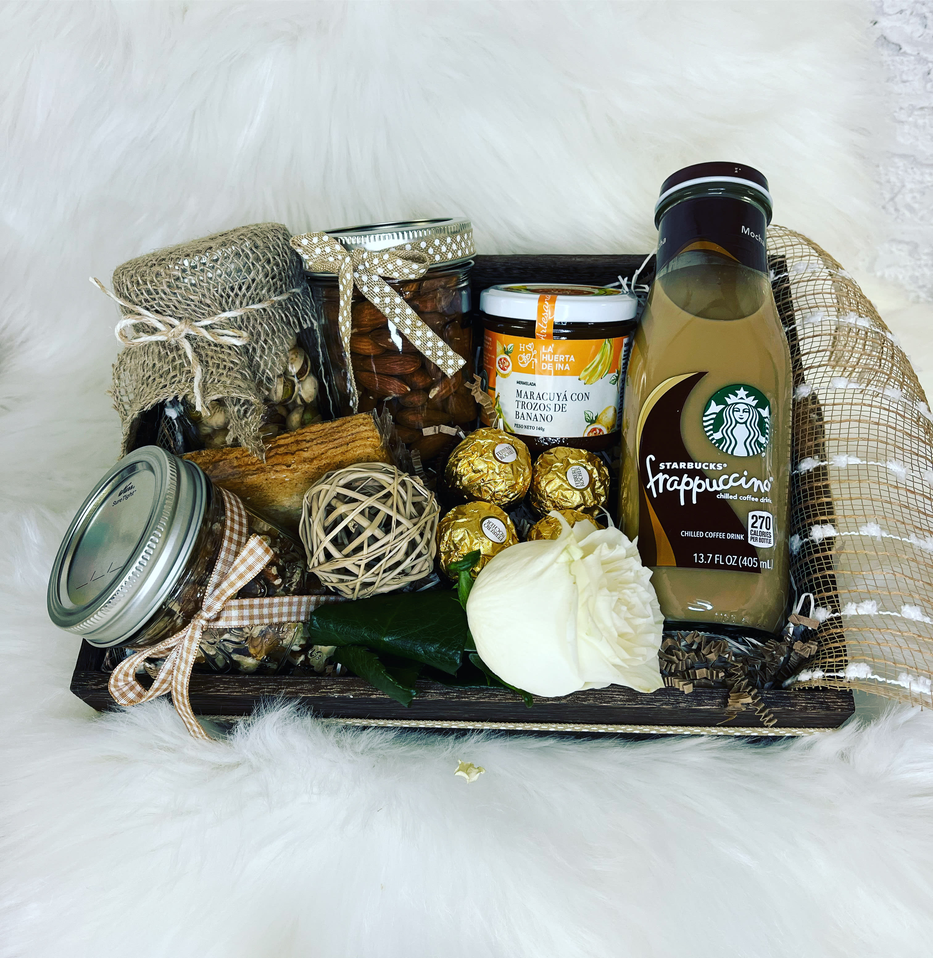 Gift basket with coffee drink, jars, chocolates, and a white rose