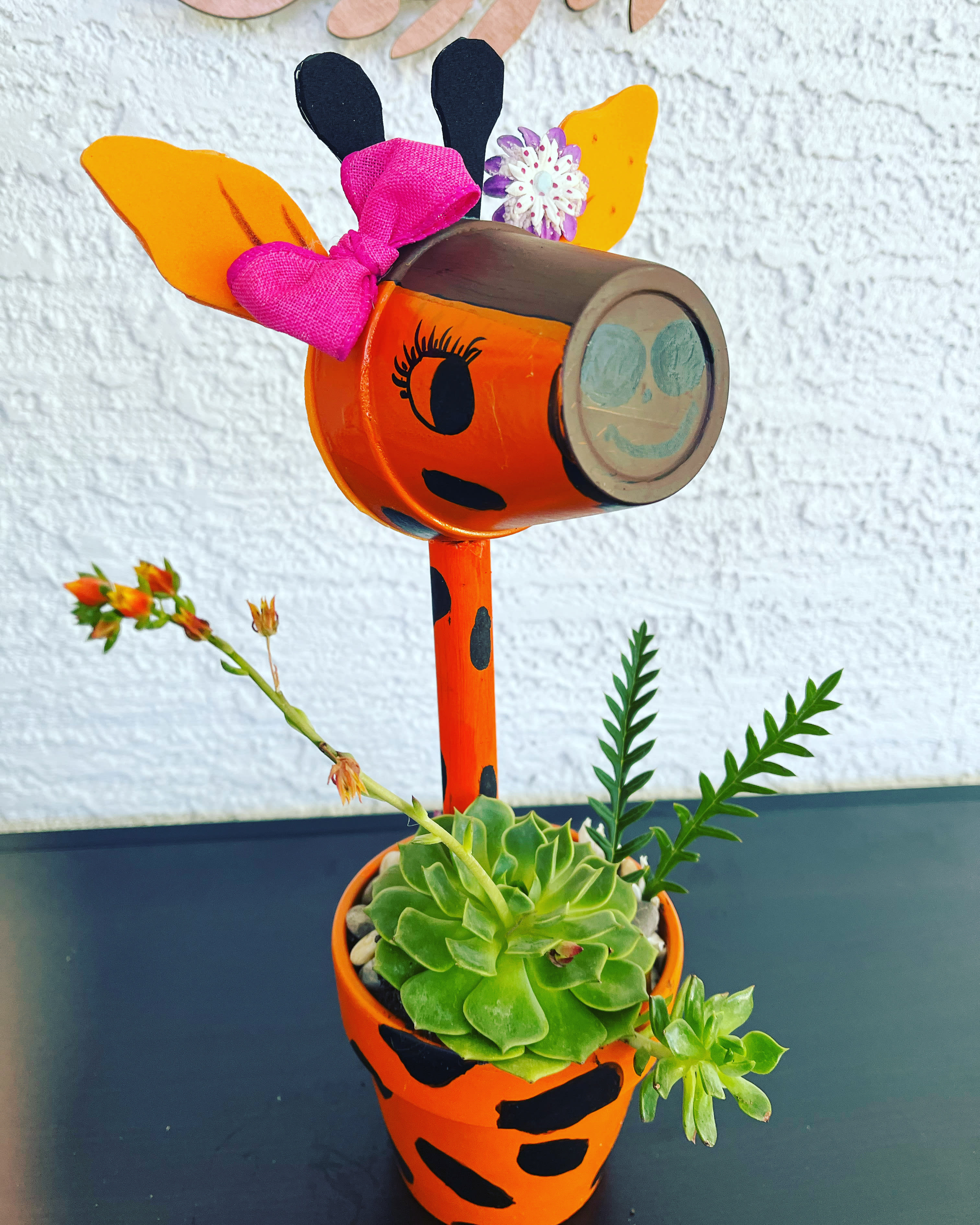 Decorative orange painted planter with a succulent and flower accents