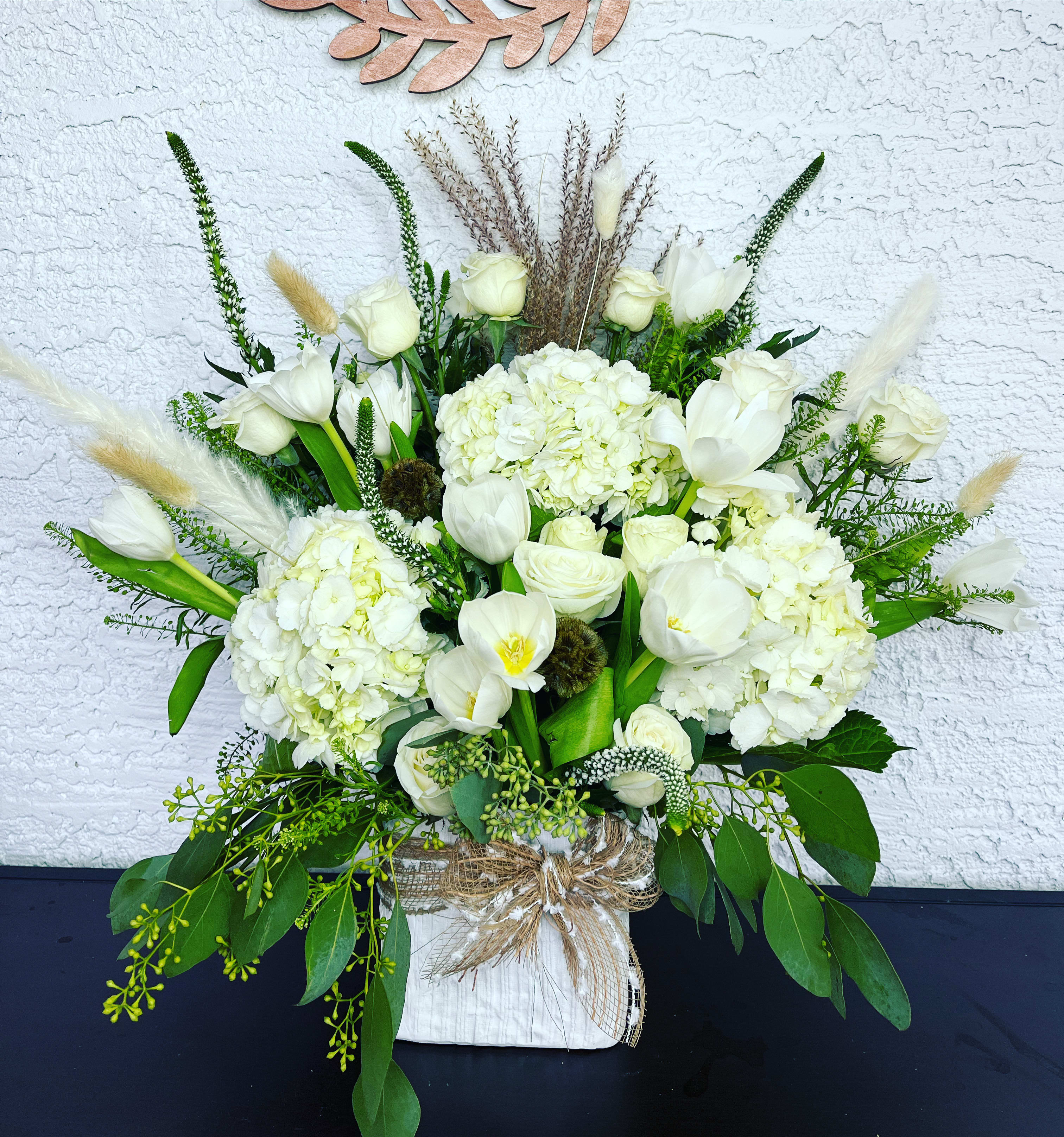 White floral arrangement with tulips and hydrangeas in a wrapped container