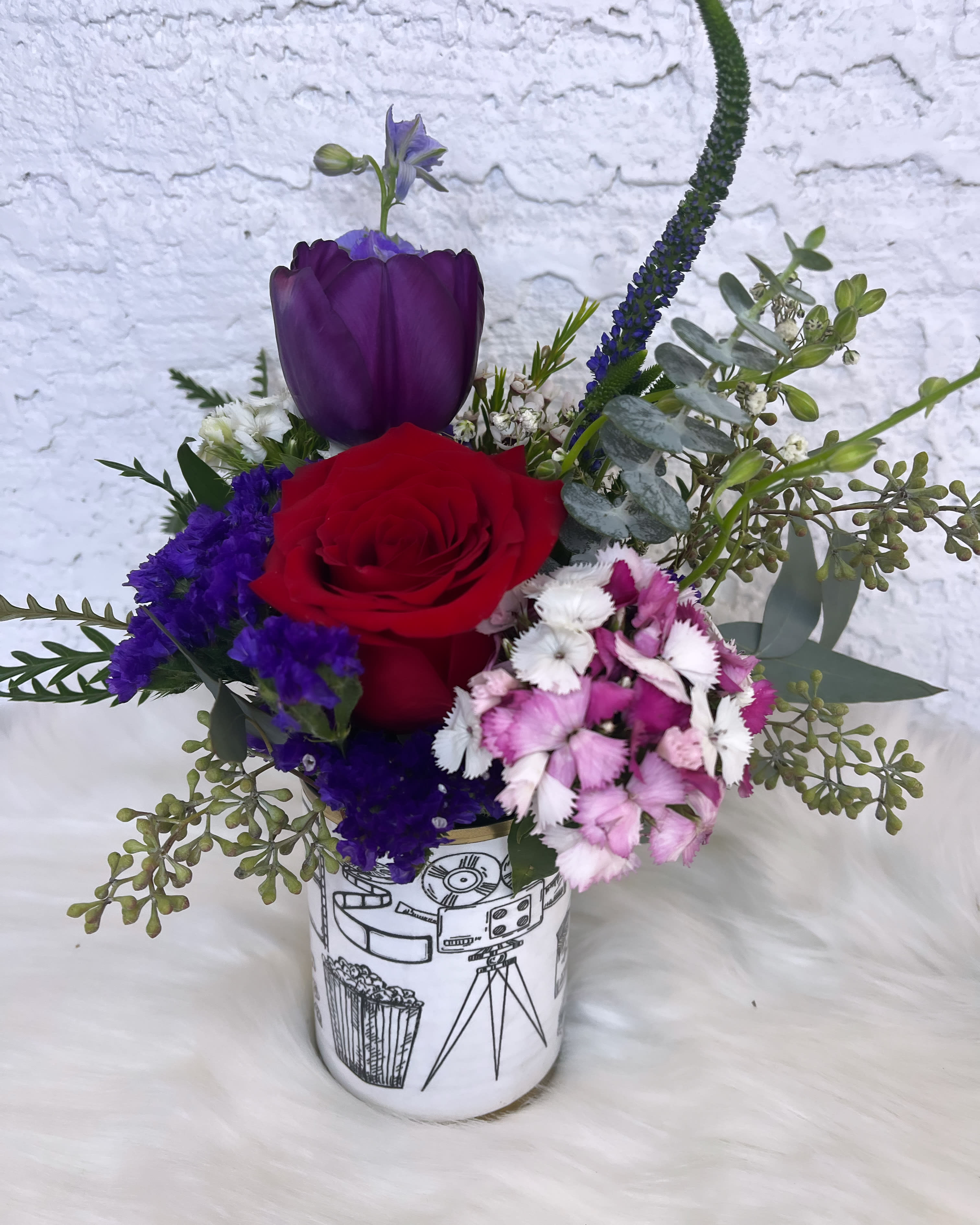 Red rose and purple tulip arrangement in a printed ceramic vase
