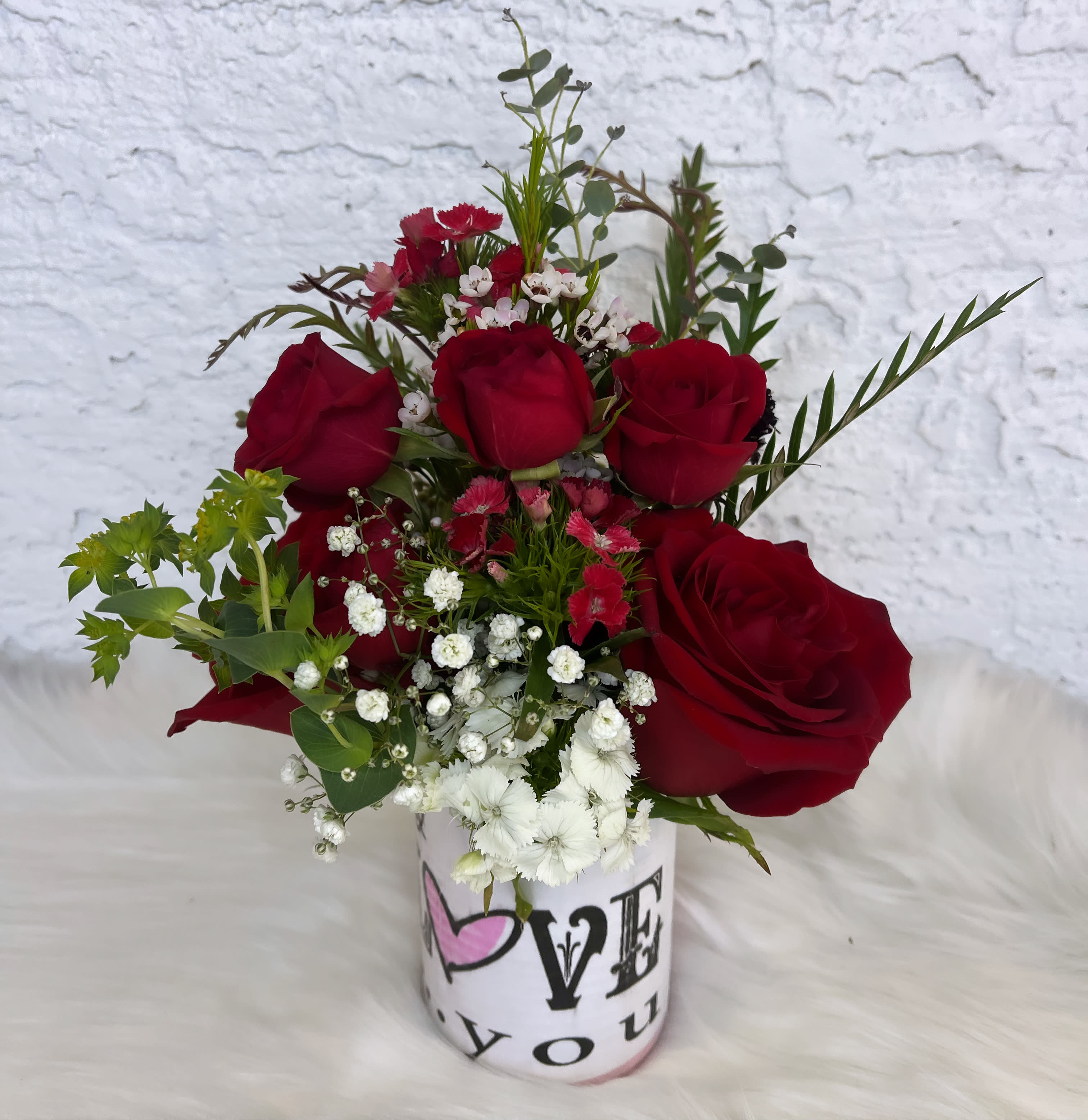 Red roses and white filler flowers in a printed vase