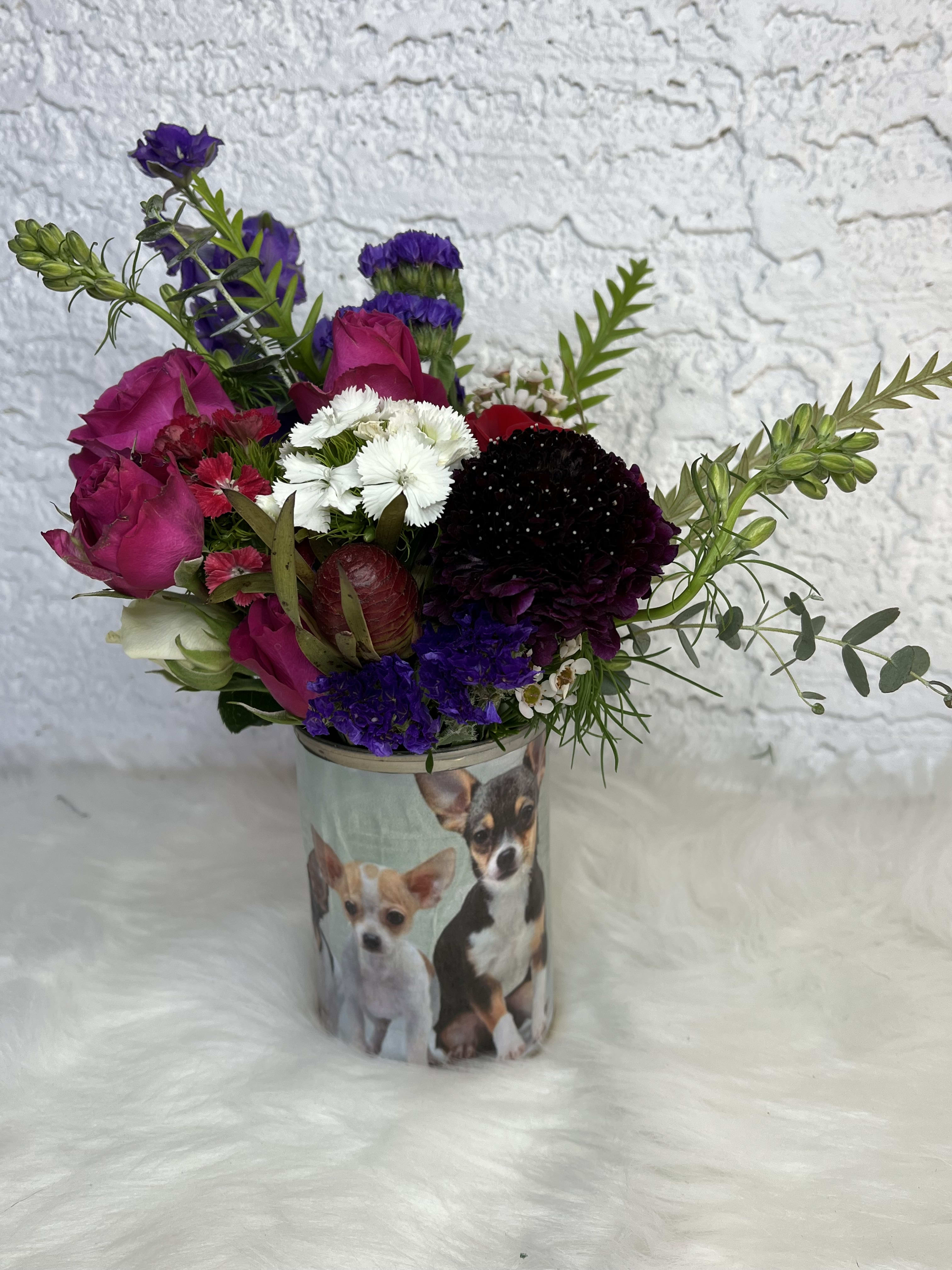 Mixed bouquet in a dog-printed container with pink, purple, white, and red blooms