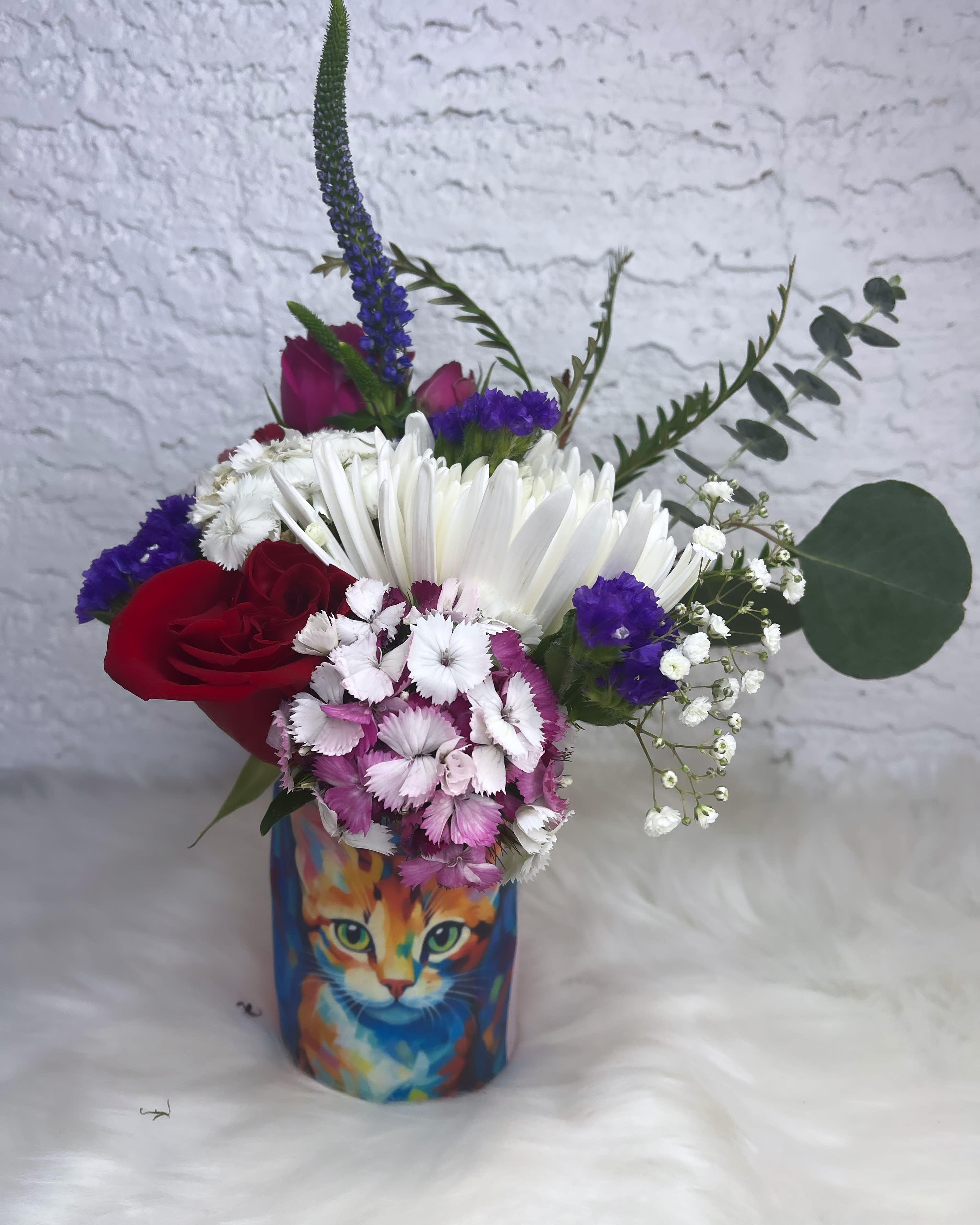 Mixed bouquet in a colorful cat-print vase with red and white flowers