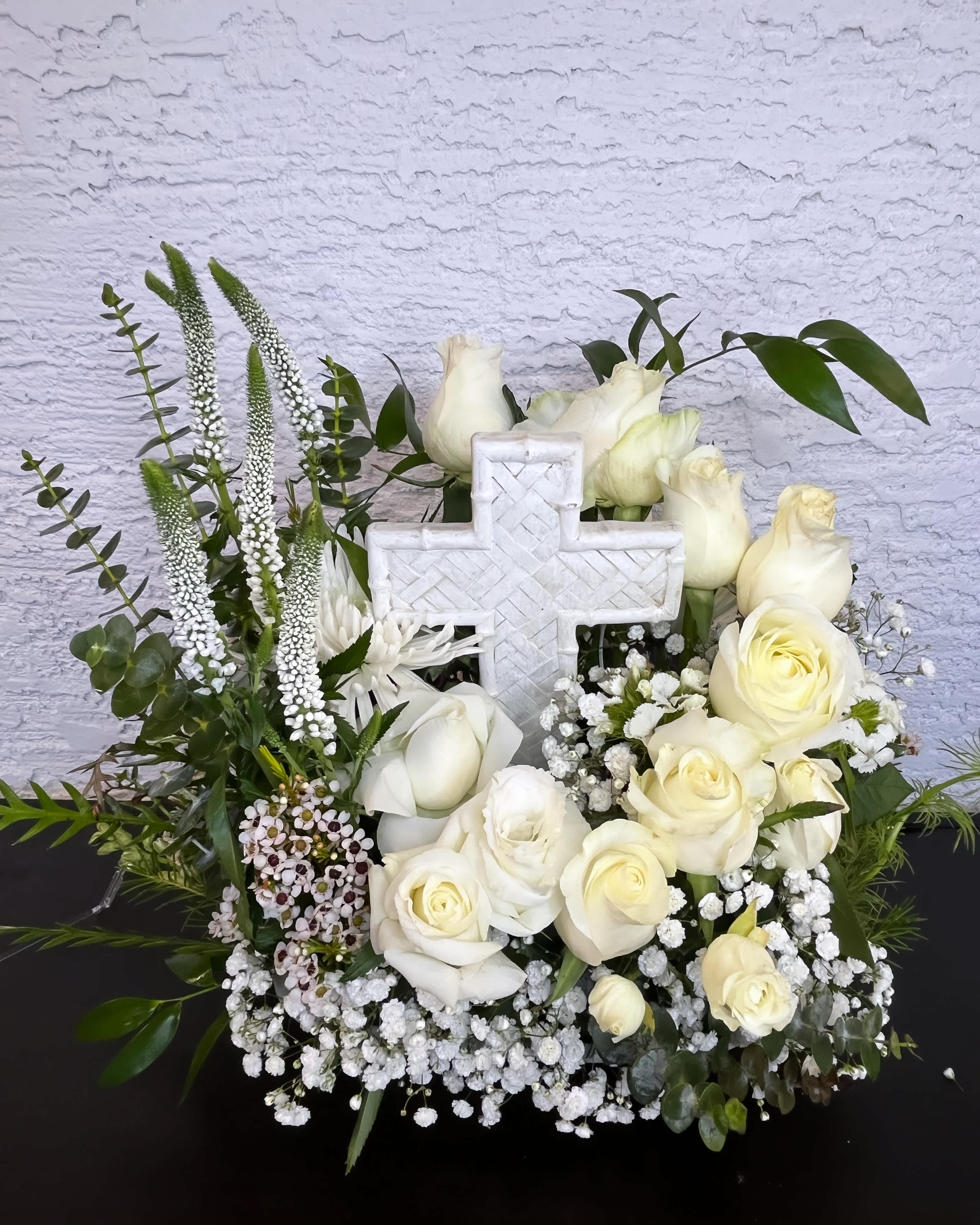 White roses and a cross centerpiece with greenery