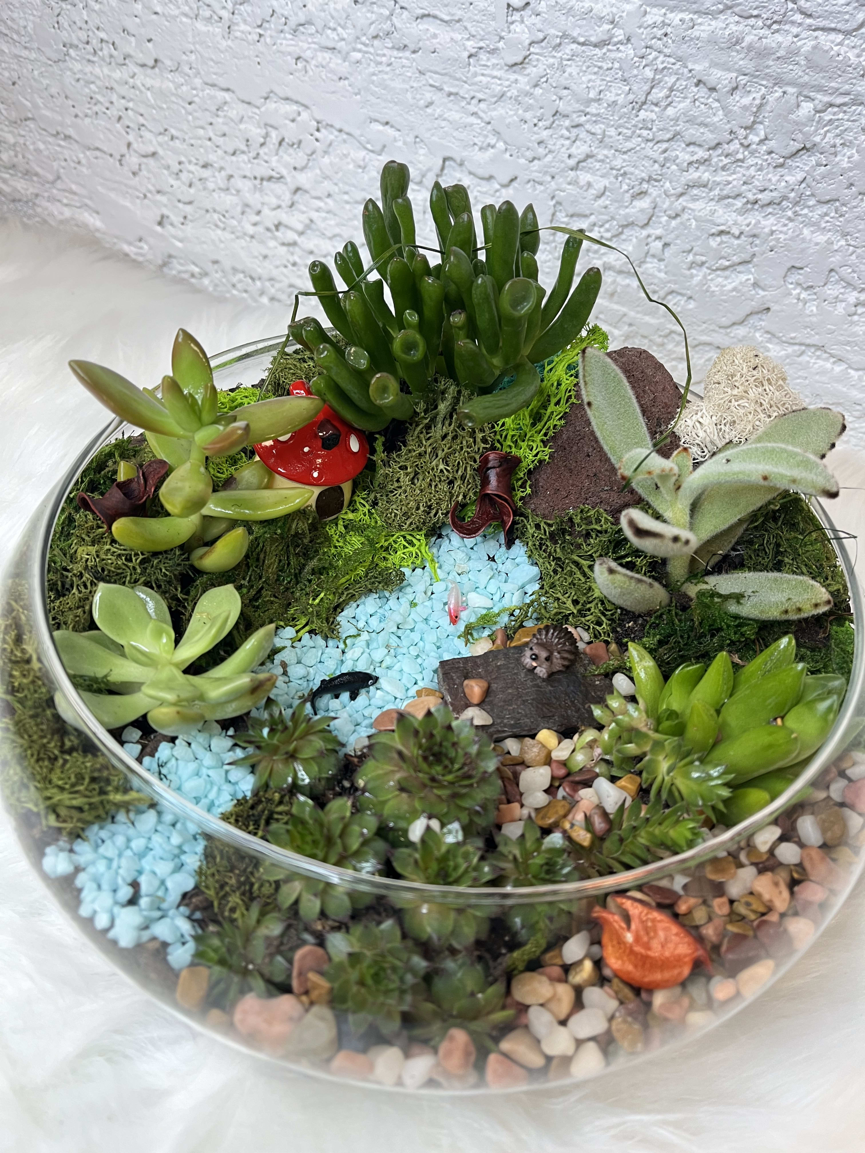 Succulent terrarium in a glass bowl with decorative stones and mini ornaments