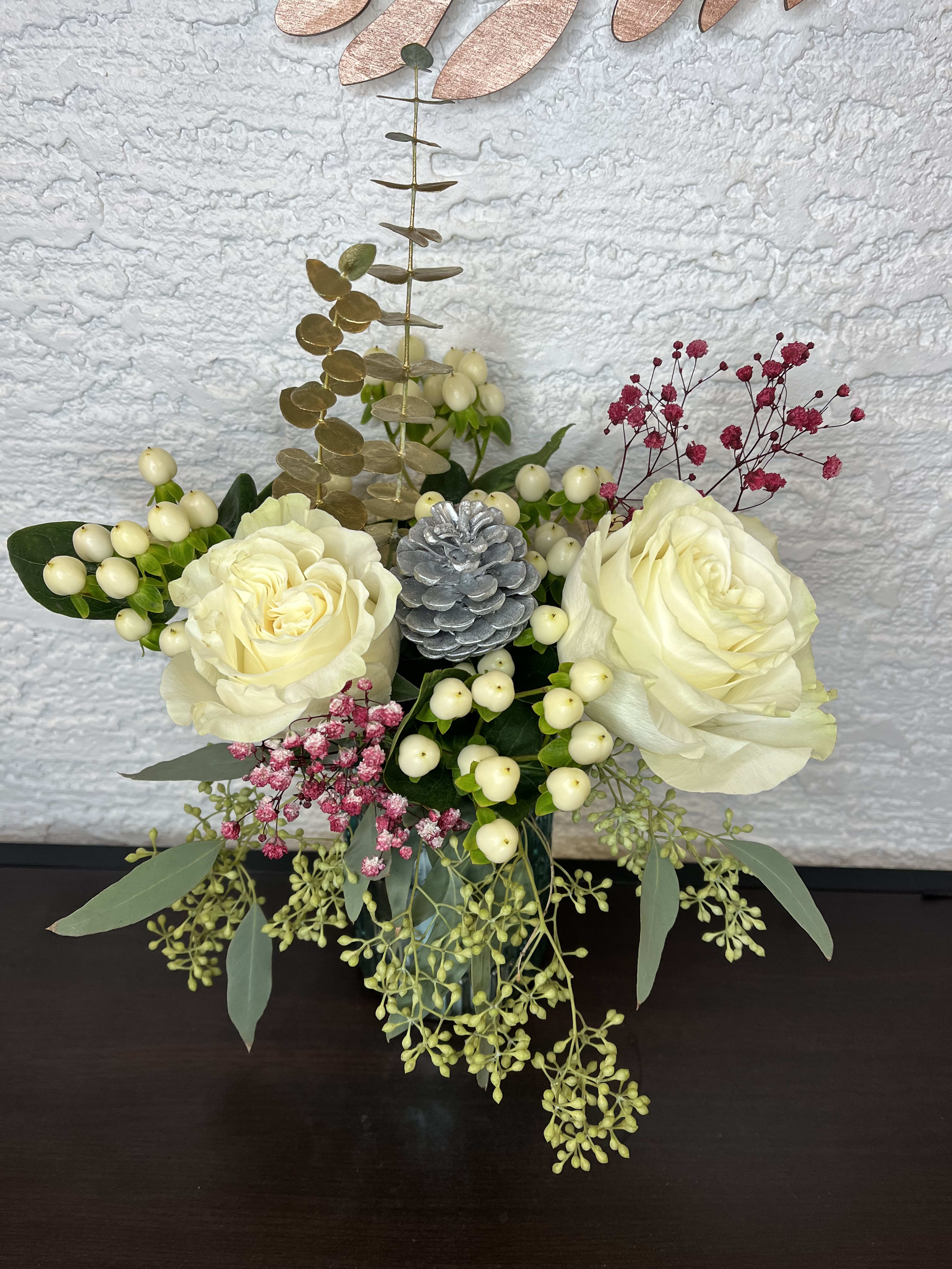 Cream rose arrangement with berries and eucalyptus in a vase
