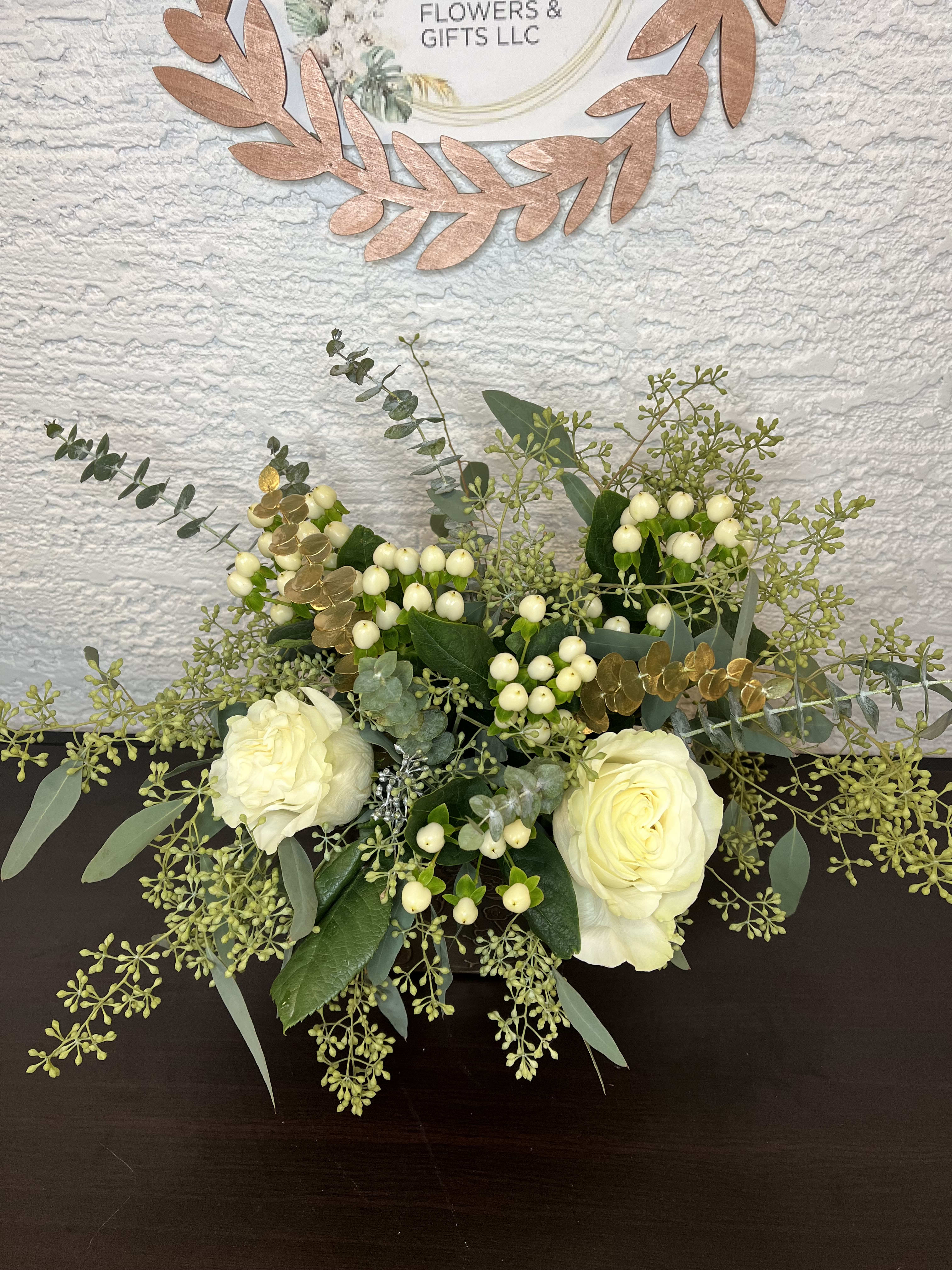 White roses with berries and eucalyptus in a low arrangement