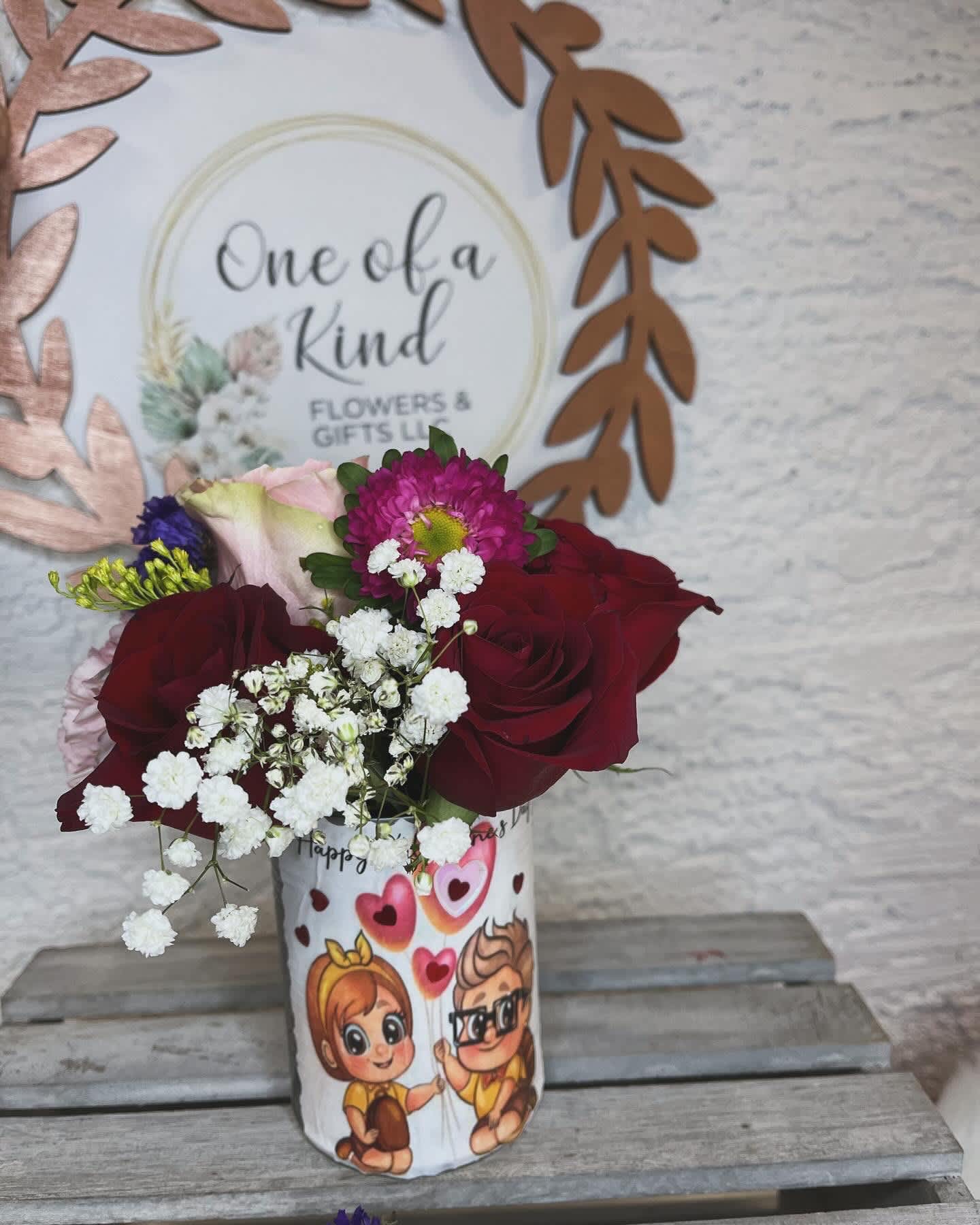 Bouquet of red roses and pink flowers in a printed gift cup