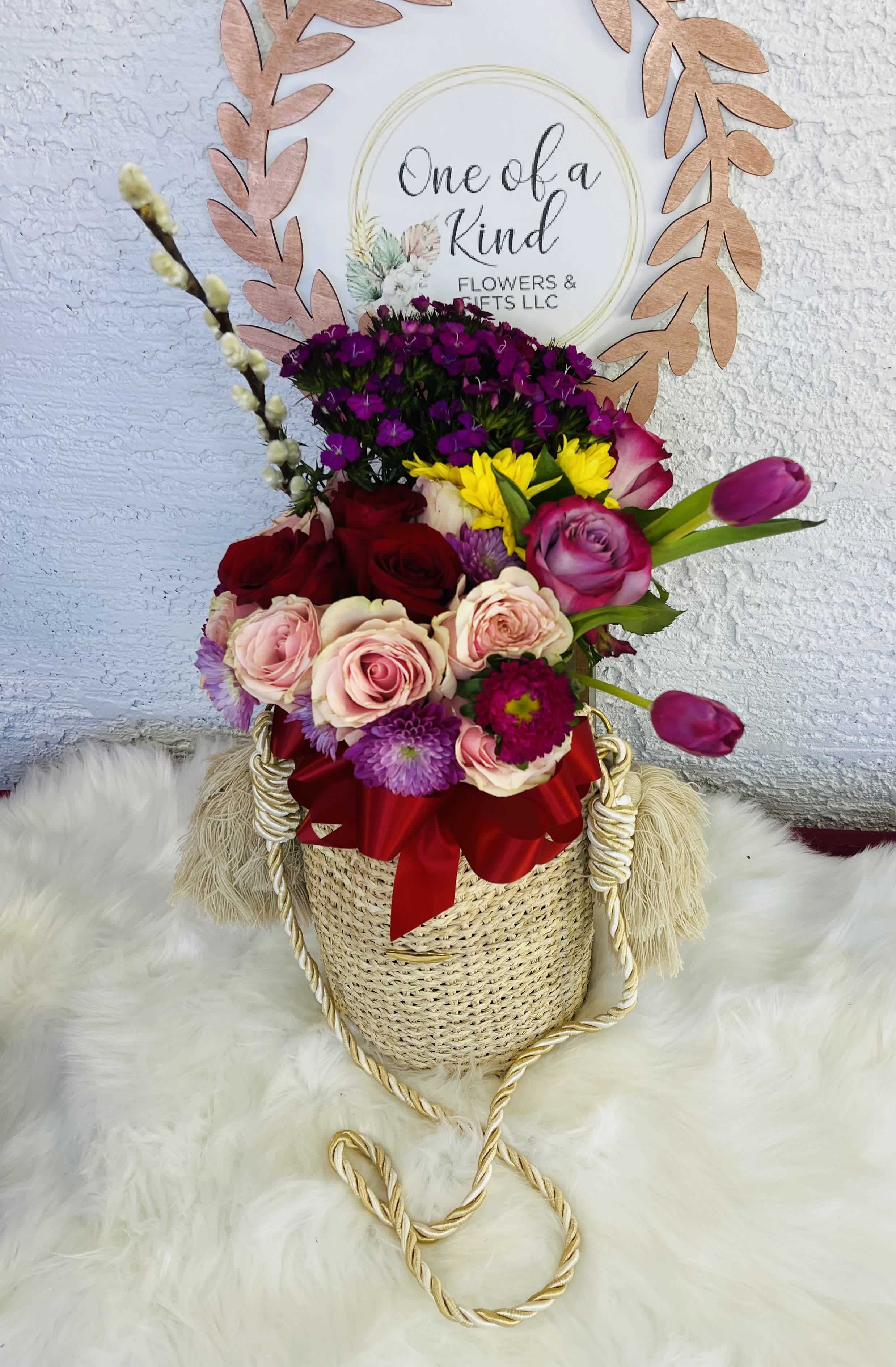 Mixed bouquet in a woven basket with a red ribbon