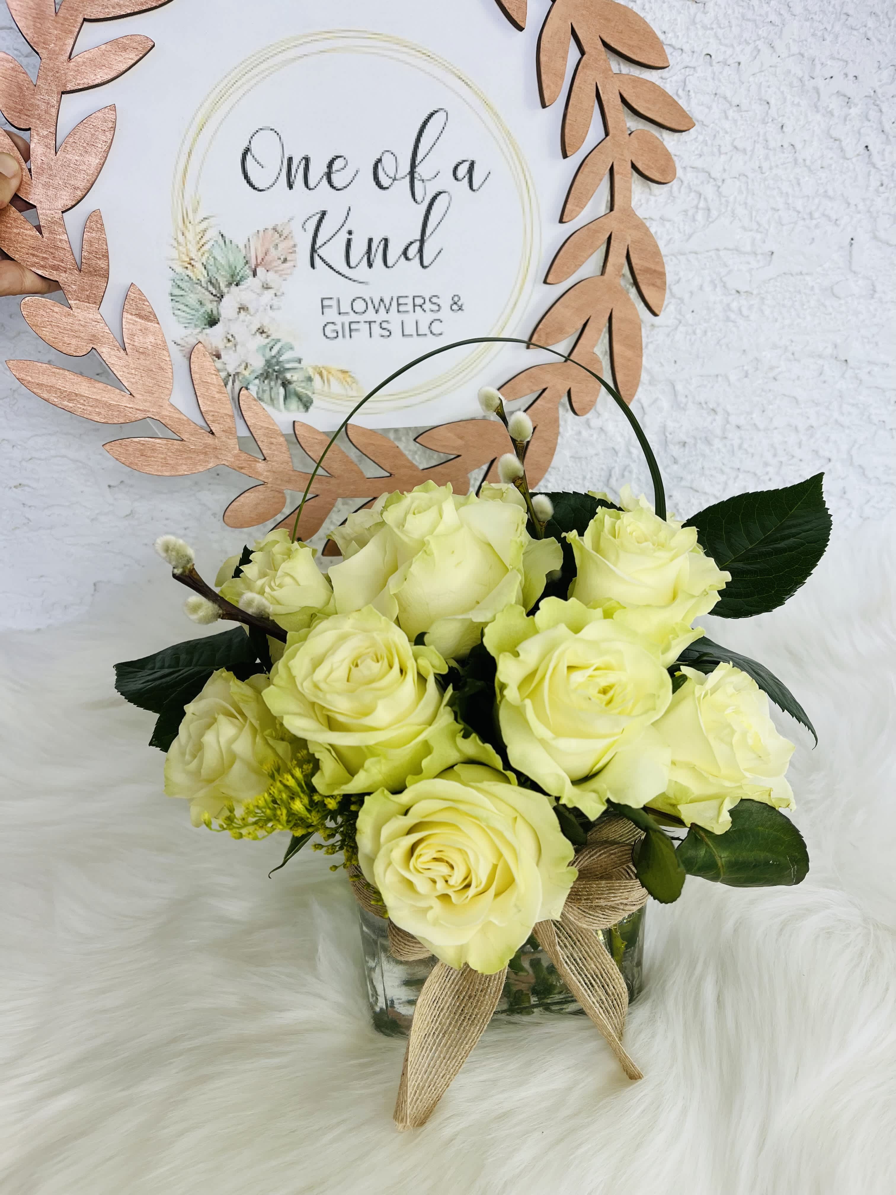Pale yellow roses in a glass vase with a burlap bow