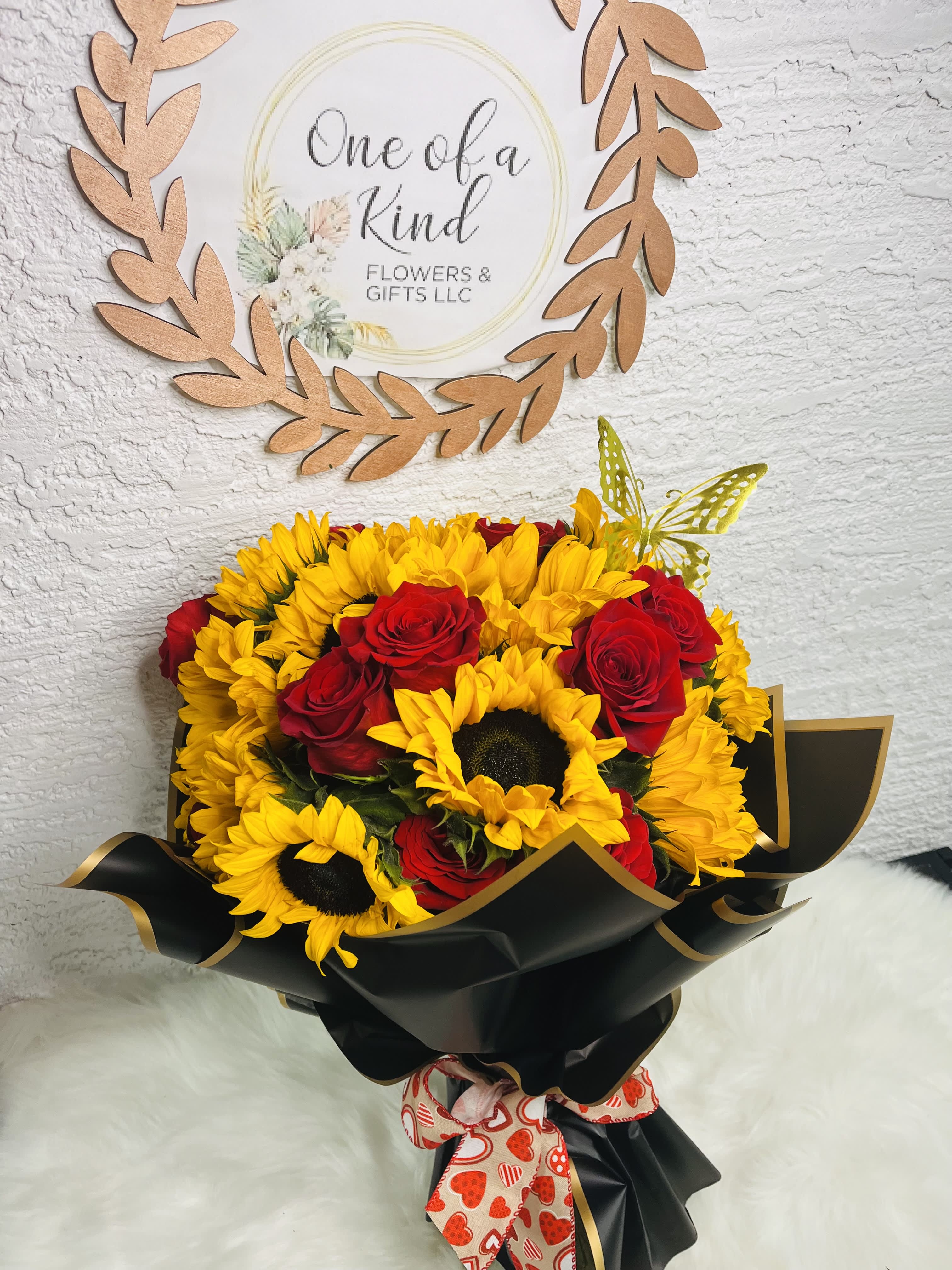 Bouquet of yellow sunflowers and red roses wrapped in black paper