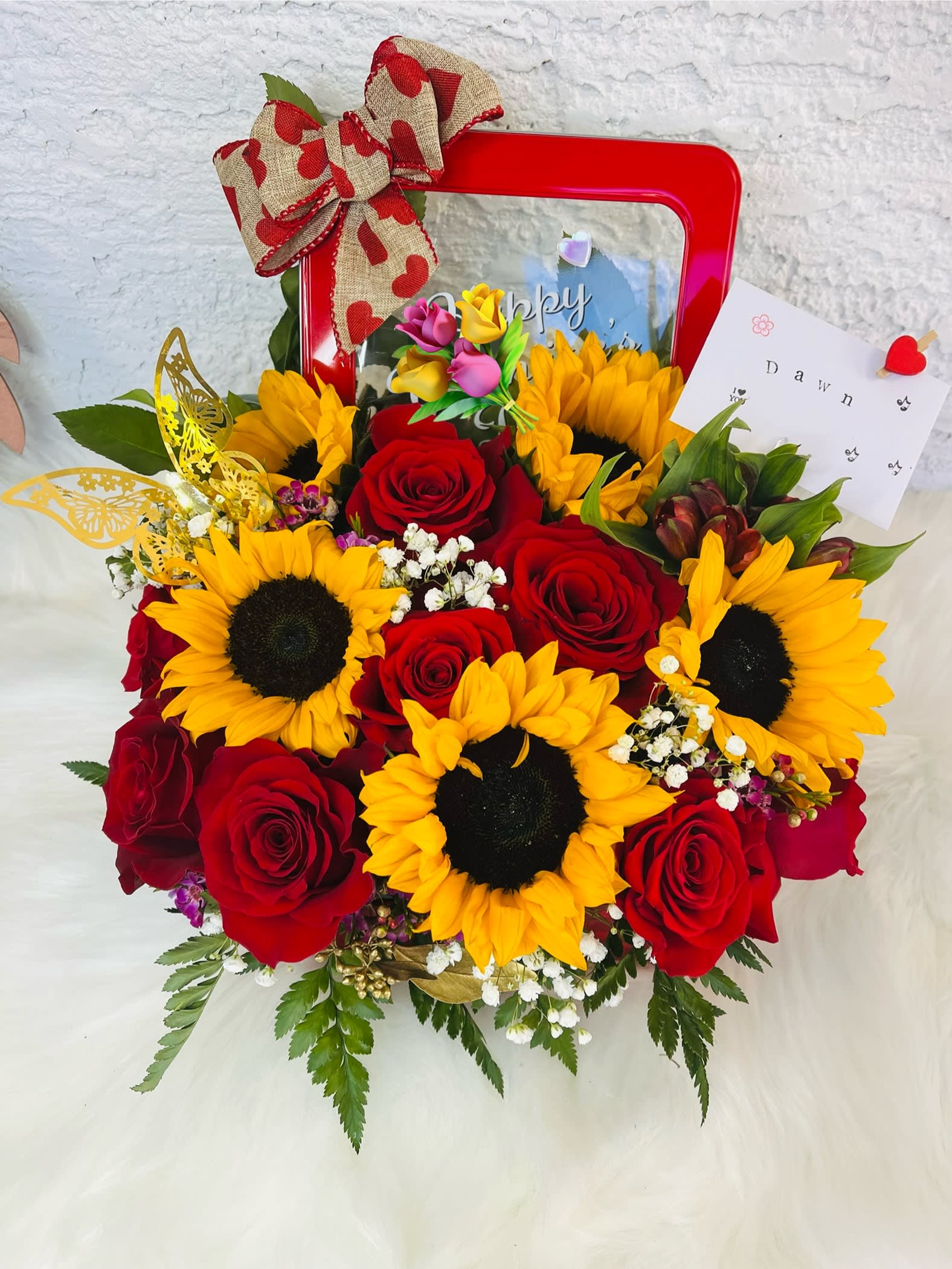Bouquet of red roses and yellow sunflowers in a red gift box