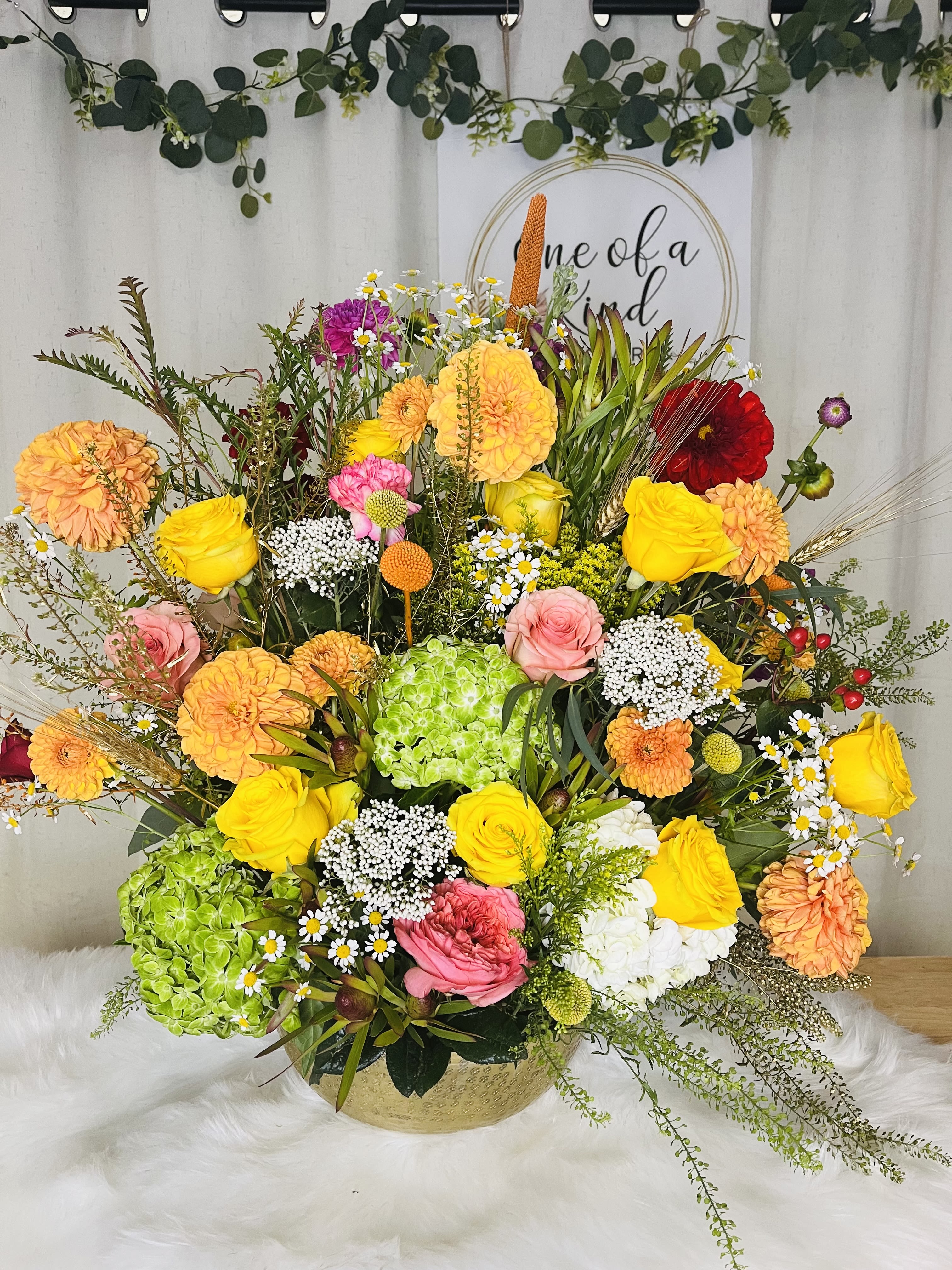 Colorful mixed flower arrangement in a gold bowl vase