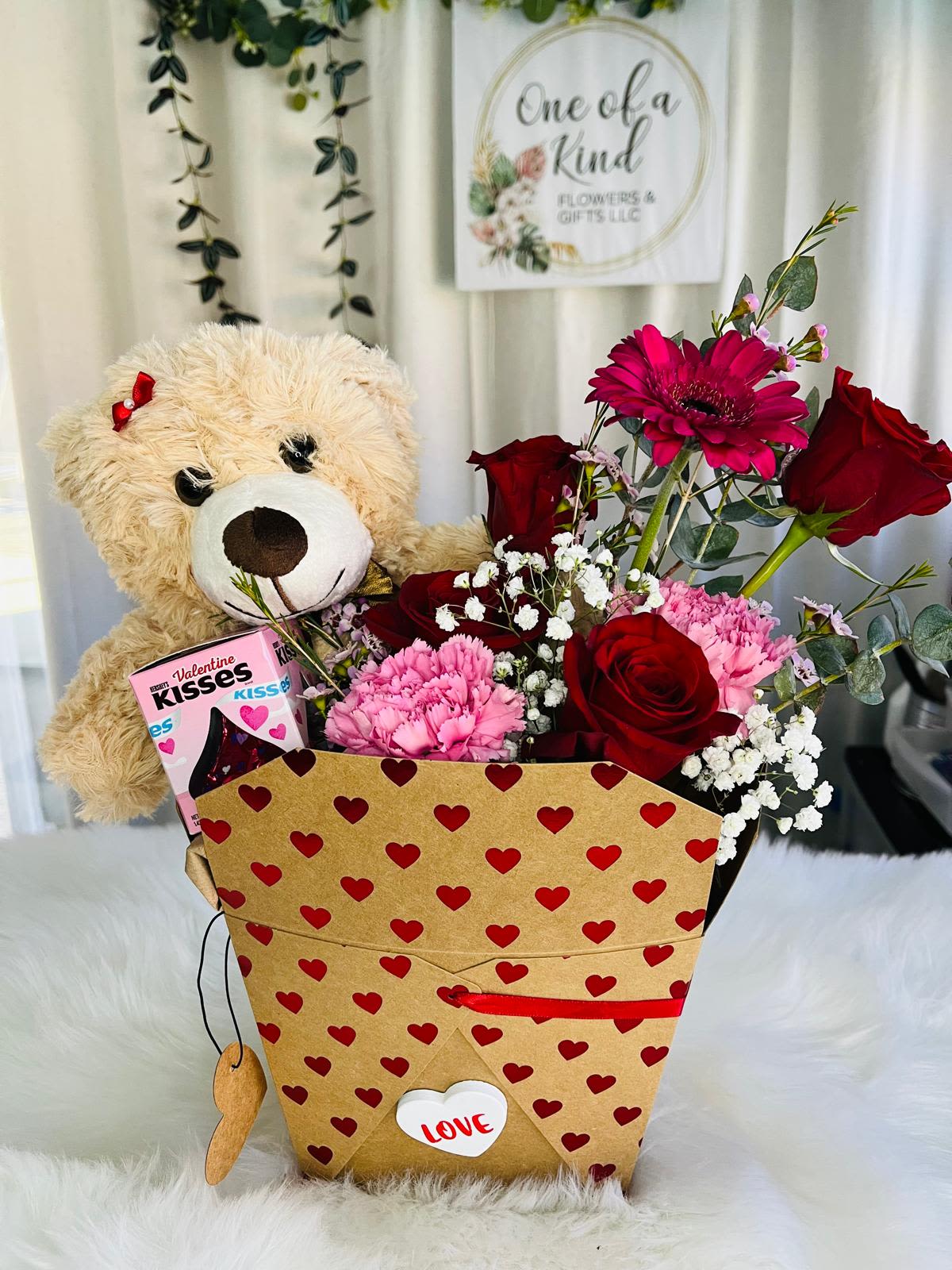 Teddy bear and red flower arrangement in a heart-patterned gift box