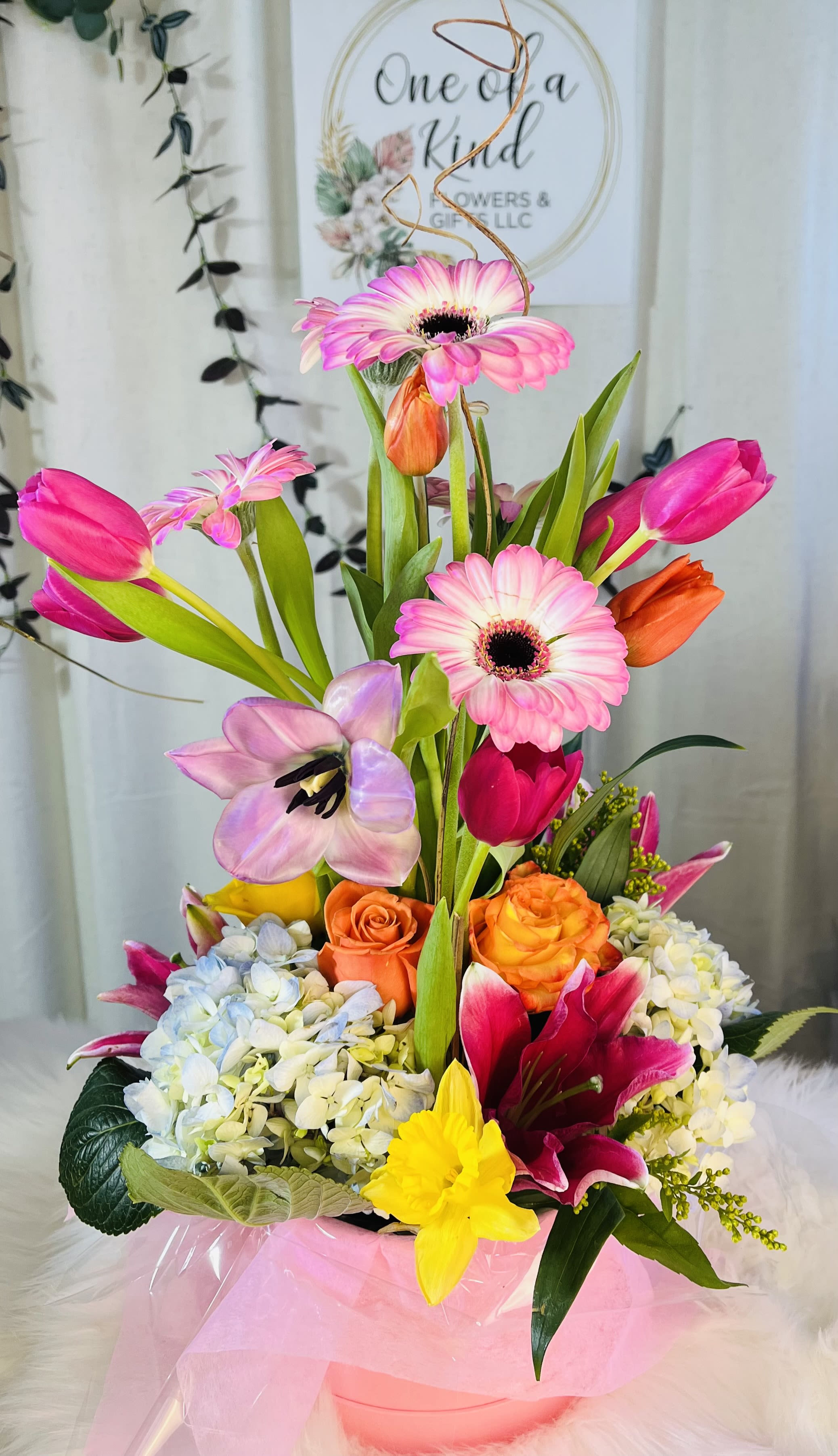 Bright mixed bouquet in a pink wrapped container with tulips and gerbera daisies