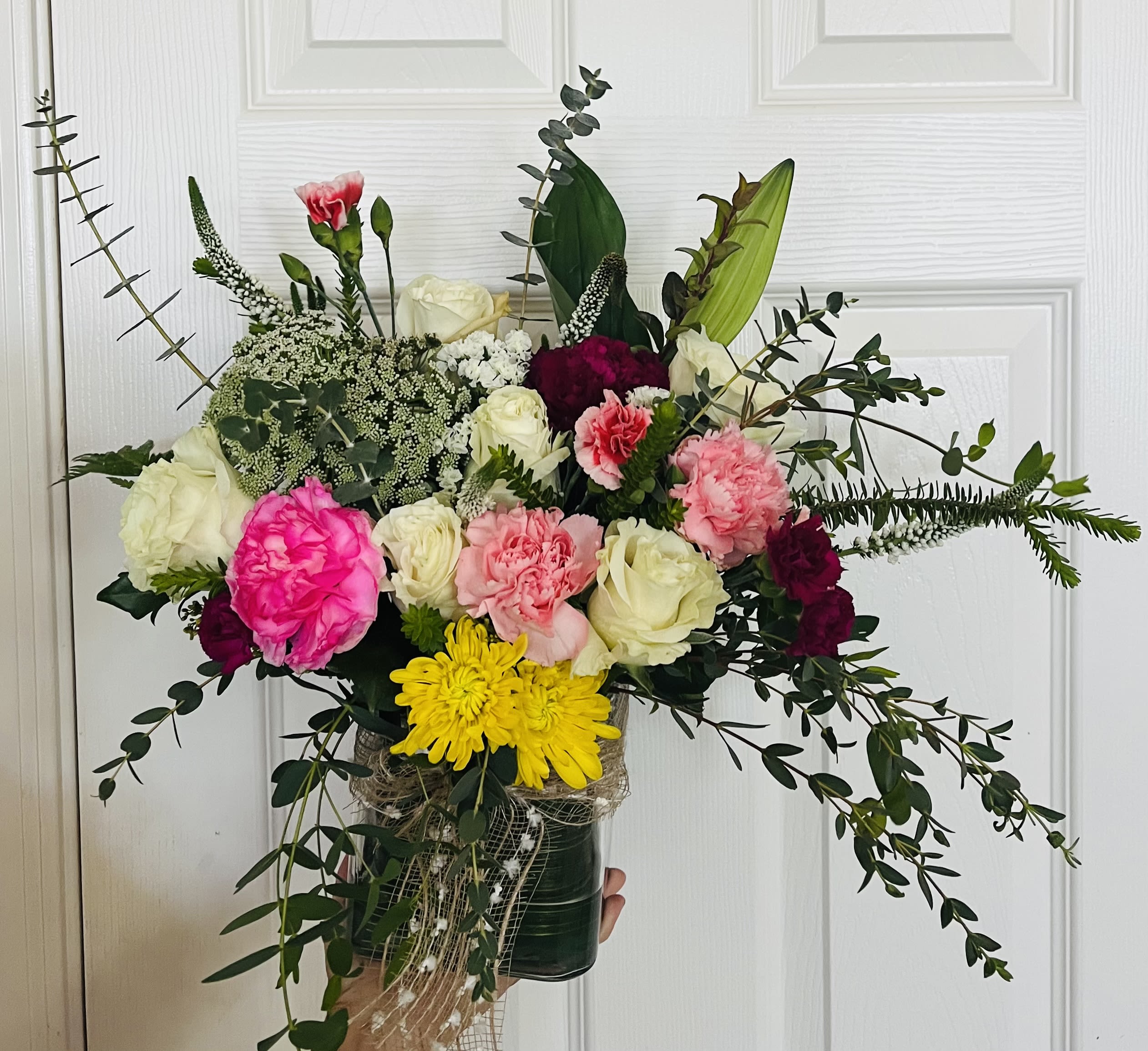 Mixed bouquet of roses, carnations, and chrysanthemums in a dark vase