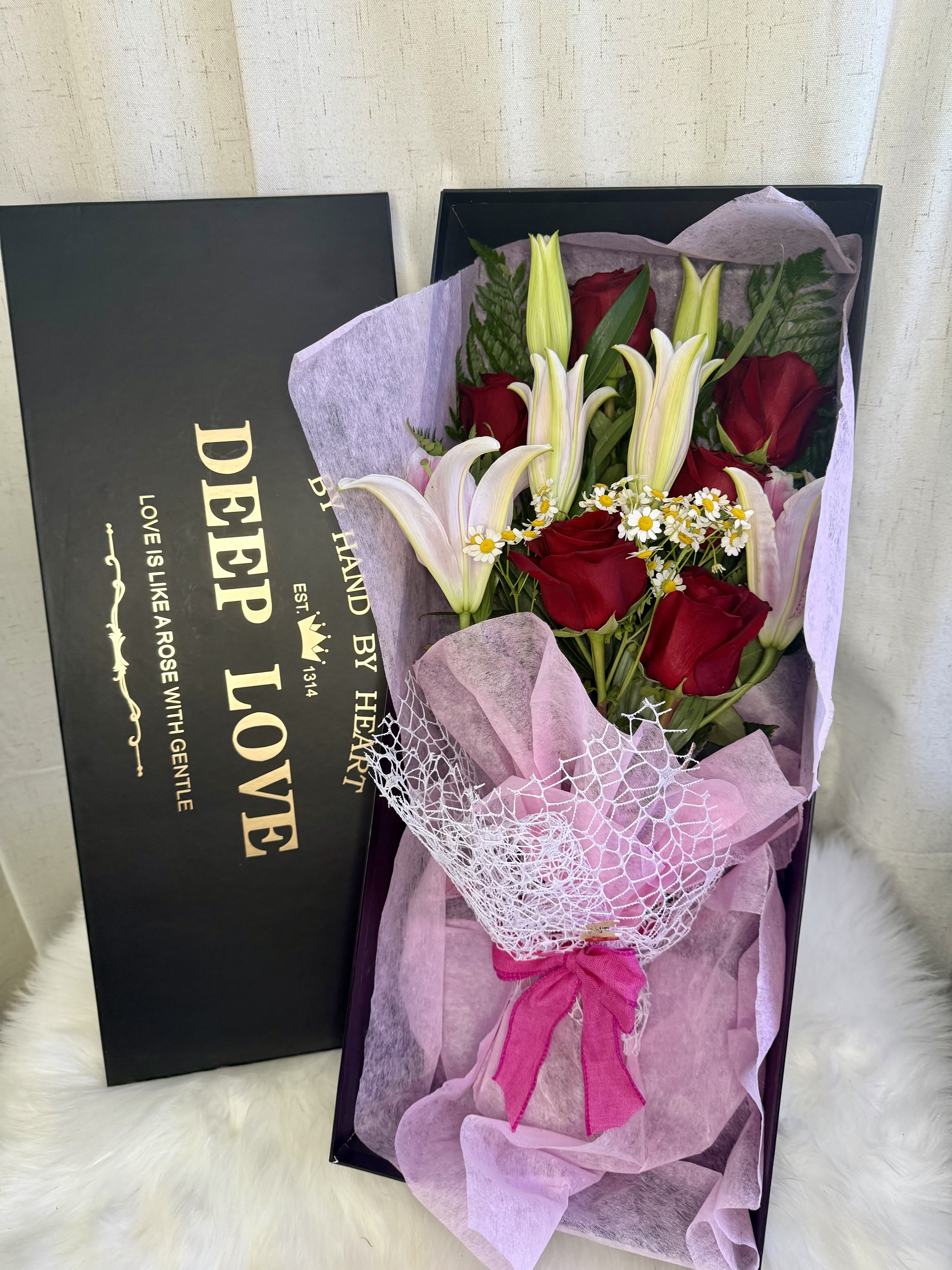 Red roses and white lilies in a gift box with pink wrapping