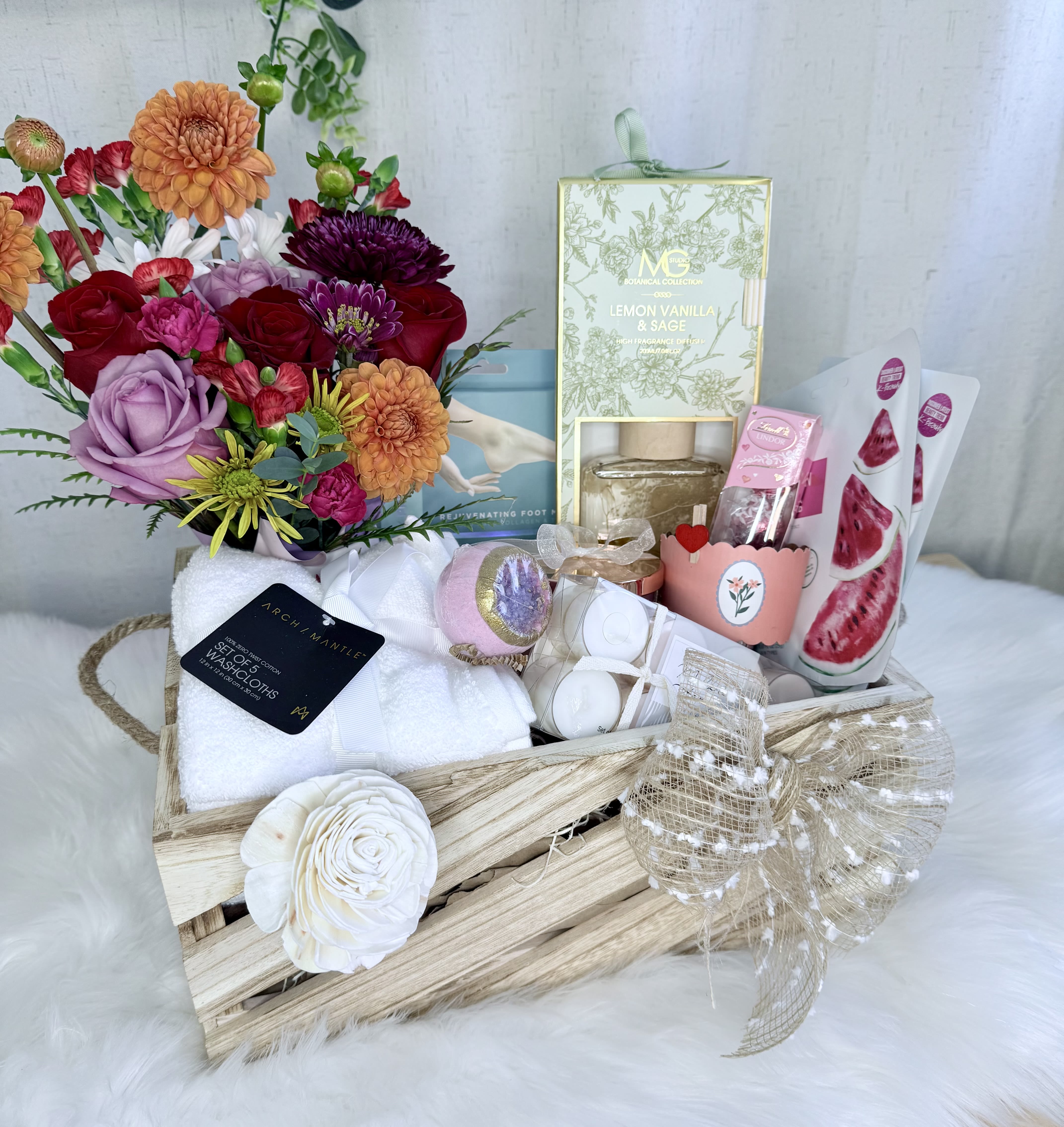 Gift basket with mixed flowers, candles, towels, and bath items