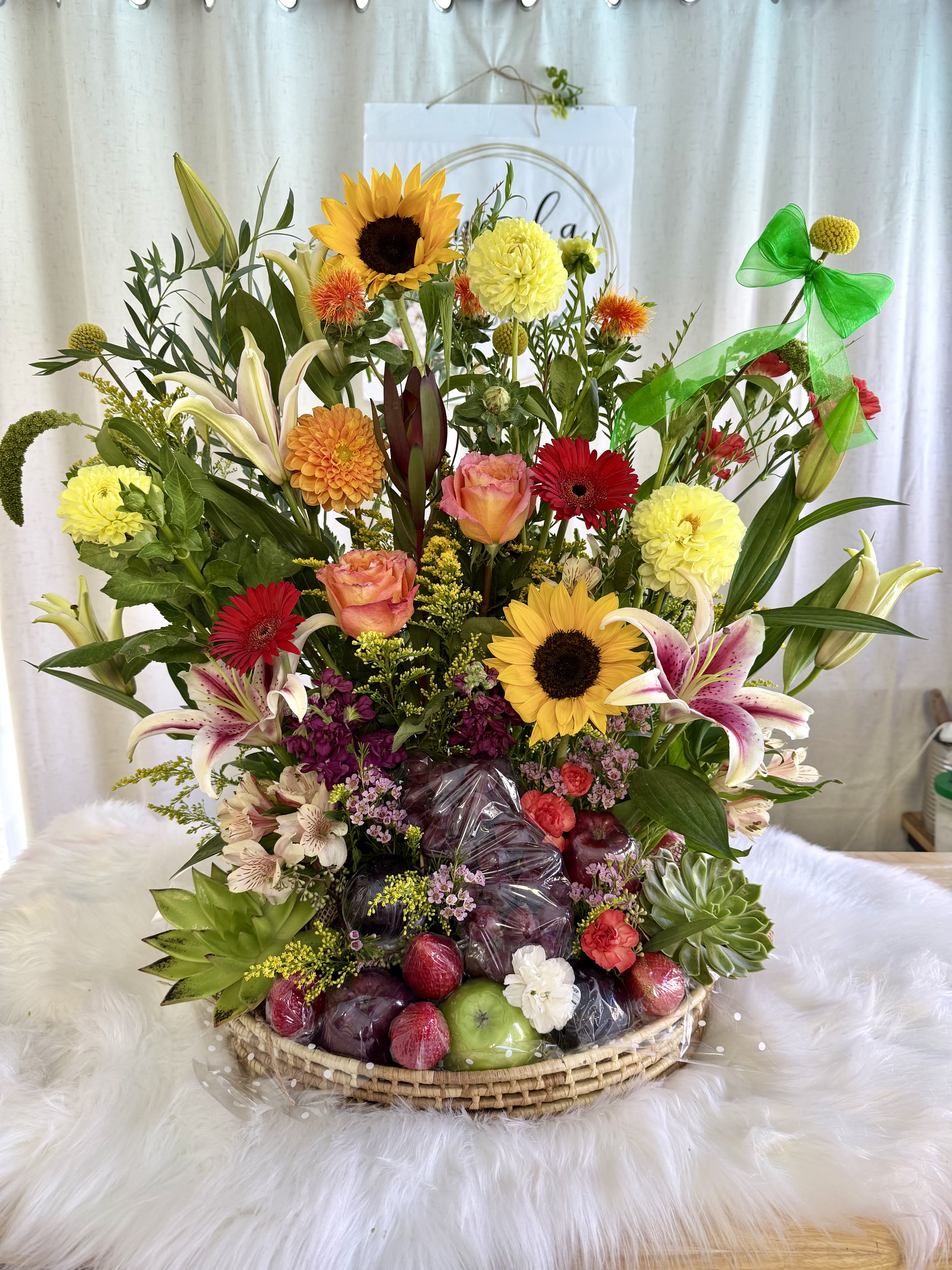 Mixed flower basket with sunflowers, lilies, roses, and fruit