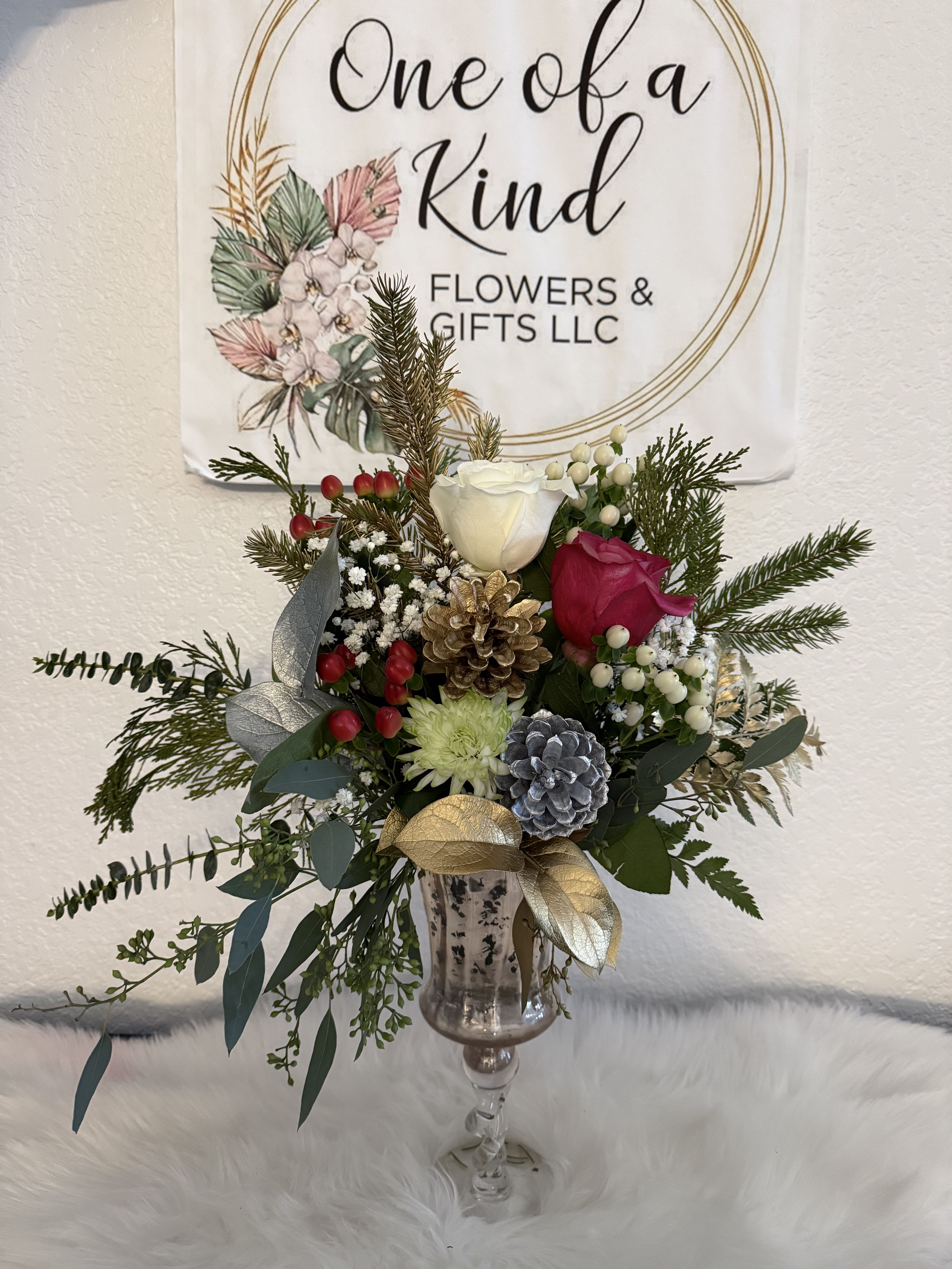 Holiday bouquet in a glass vase with roses, pinecones, and evergreen sprigs