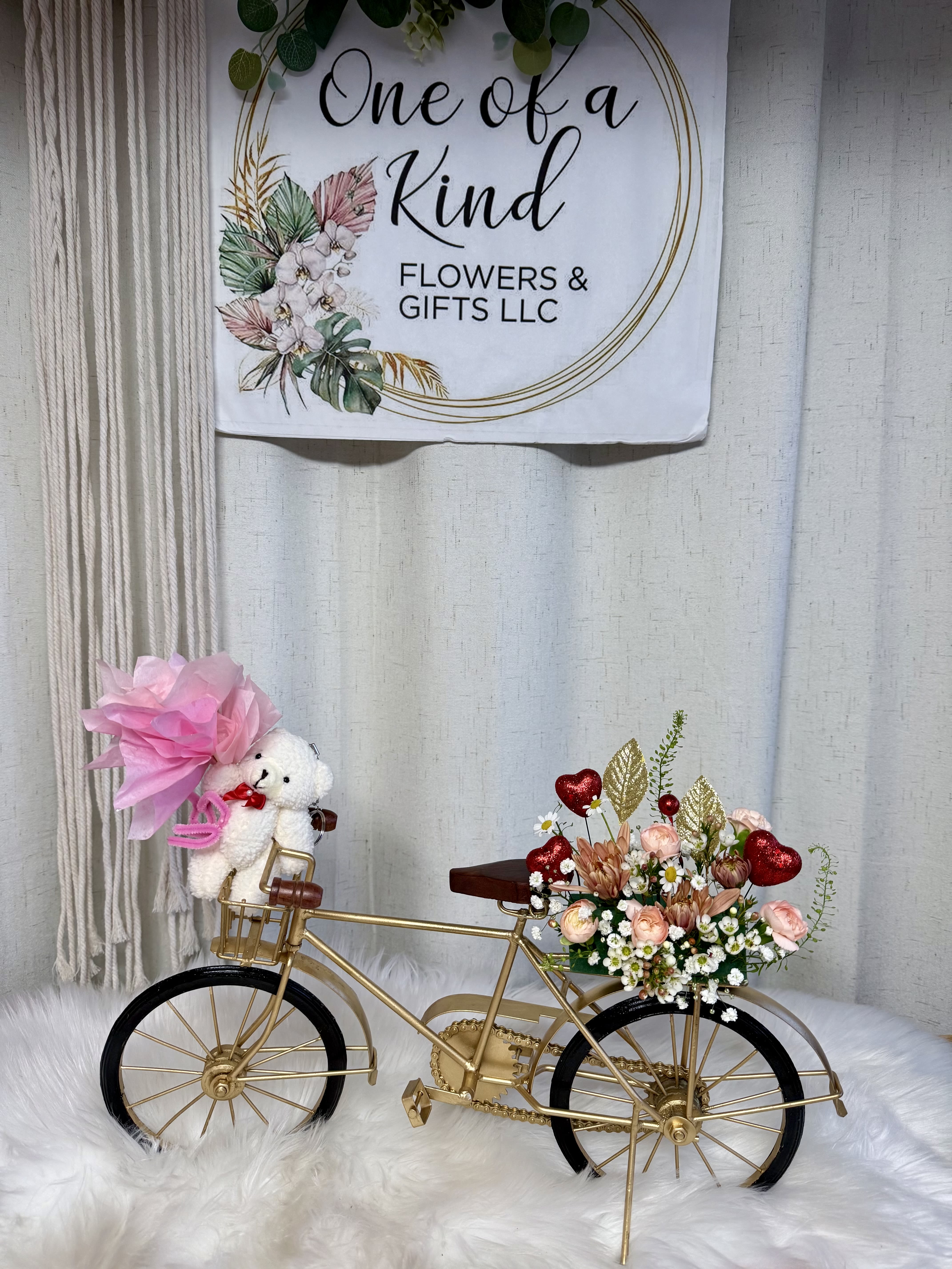 Gold bicycle decor with a small floral arrangement and teddy bear