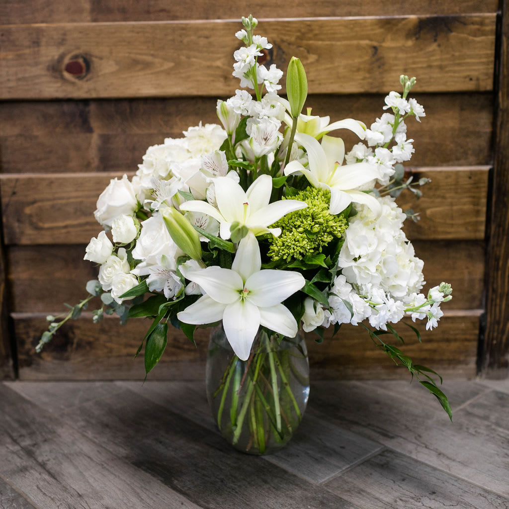 White lilies and roses arranged in a glass vase