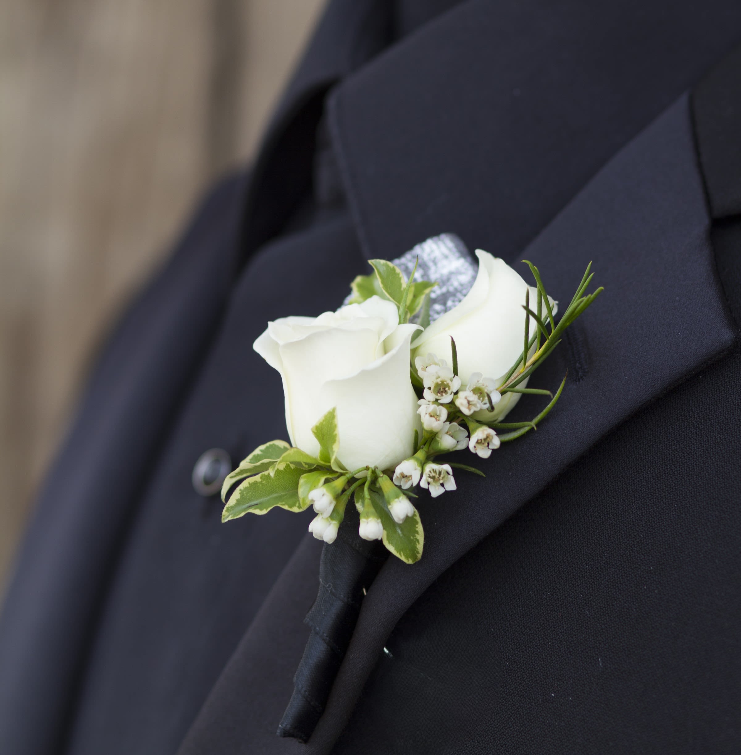 White rose boutonniere pinned to a dark suit jacket