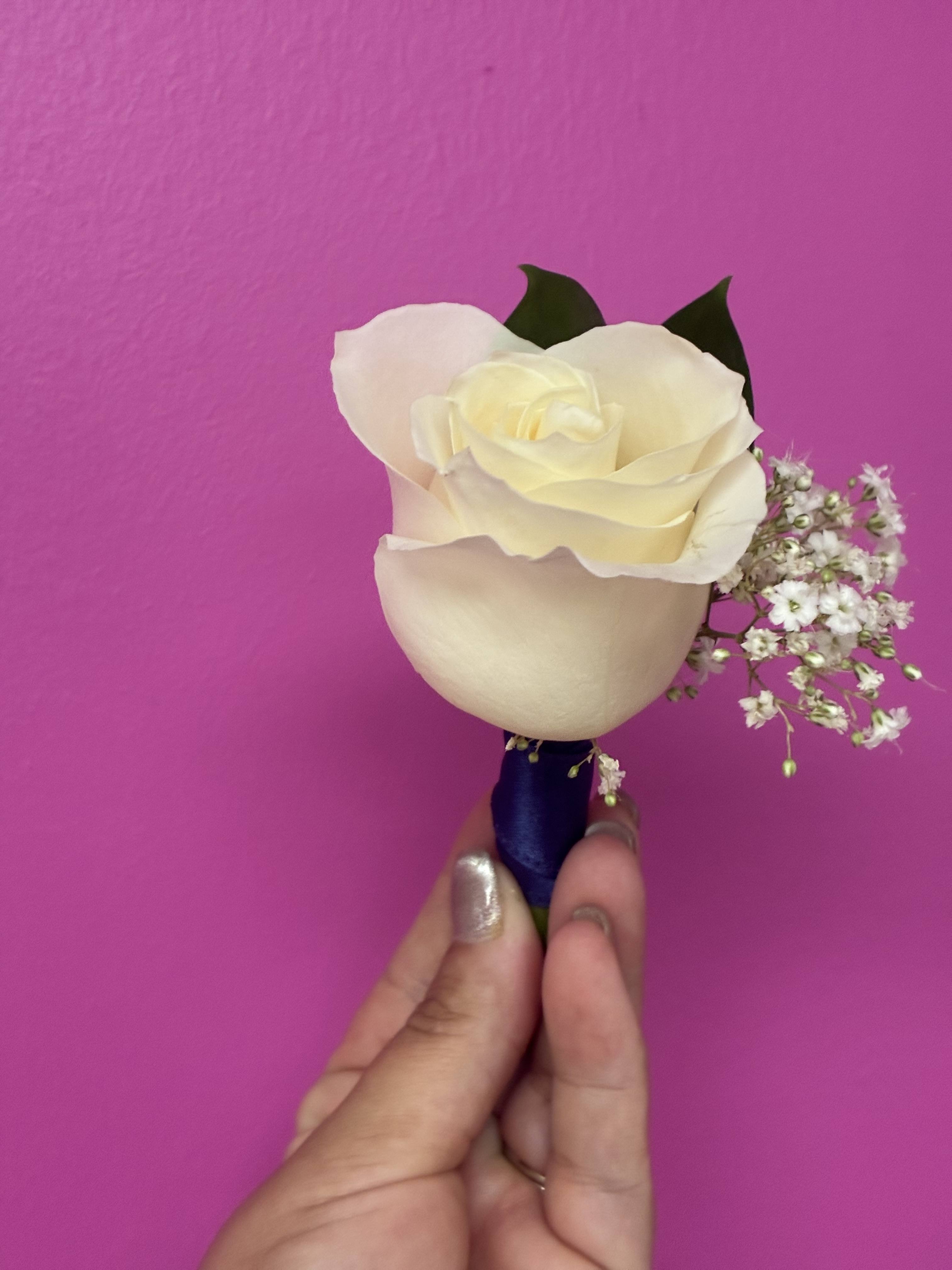 White rose boutonniere with baby's breath and dark ribbon