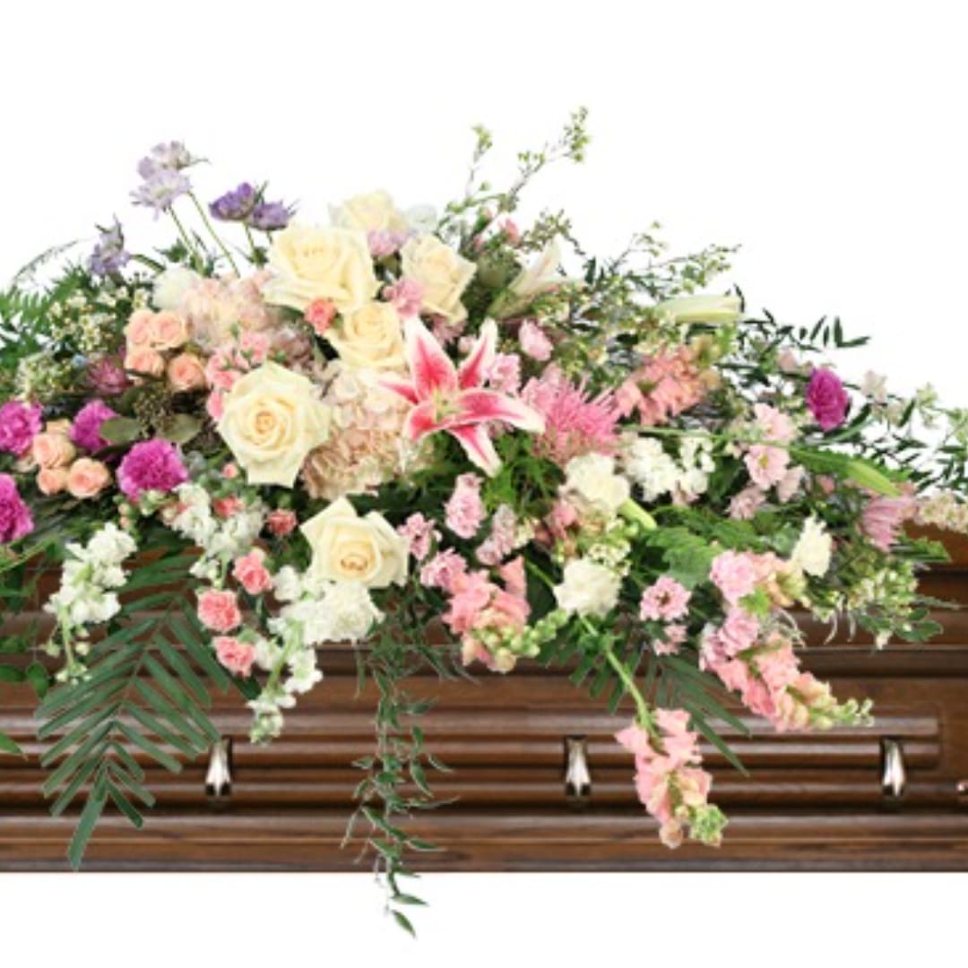 Large pastel floral spray on a wooden casket