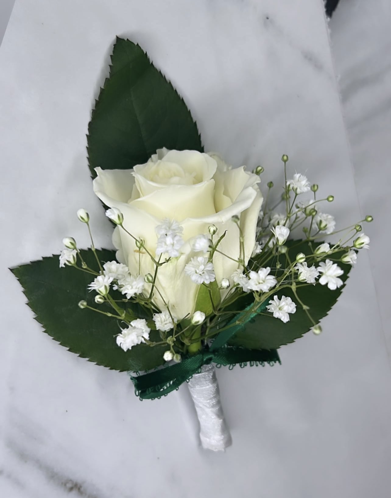 Boutonnière by Huber Heights Floral - A classic white boutonnière that compliments any suit. A perfect addition for any prom, formal, or wedding event.   IN SPECIAL INSTRUCTION BOX YOU CAN TELL US IF YOU WANT A WHITE ROSE OR A RED ONE!