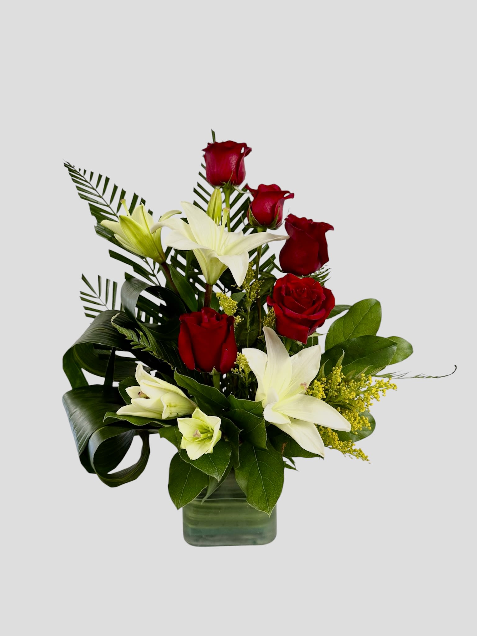 Red roses and white lilies arranged in a glass vase