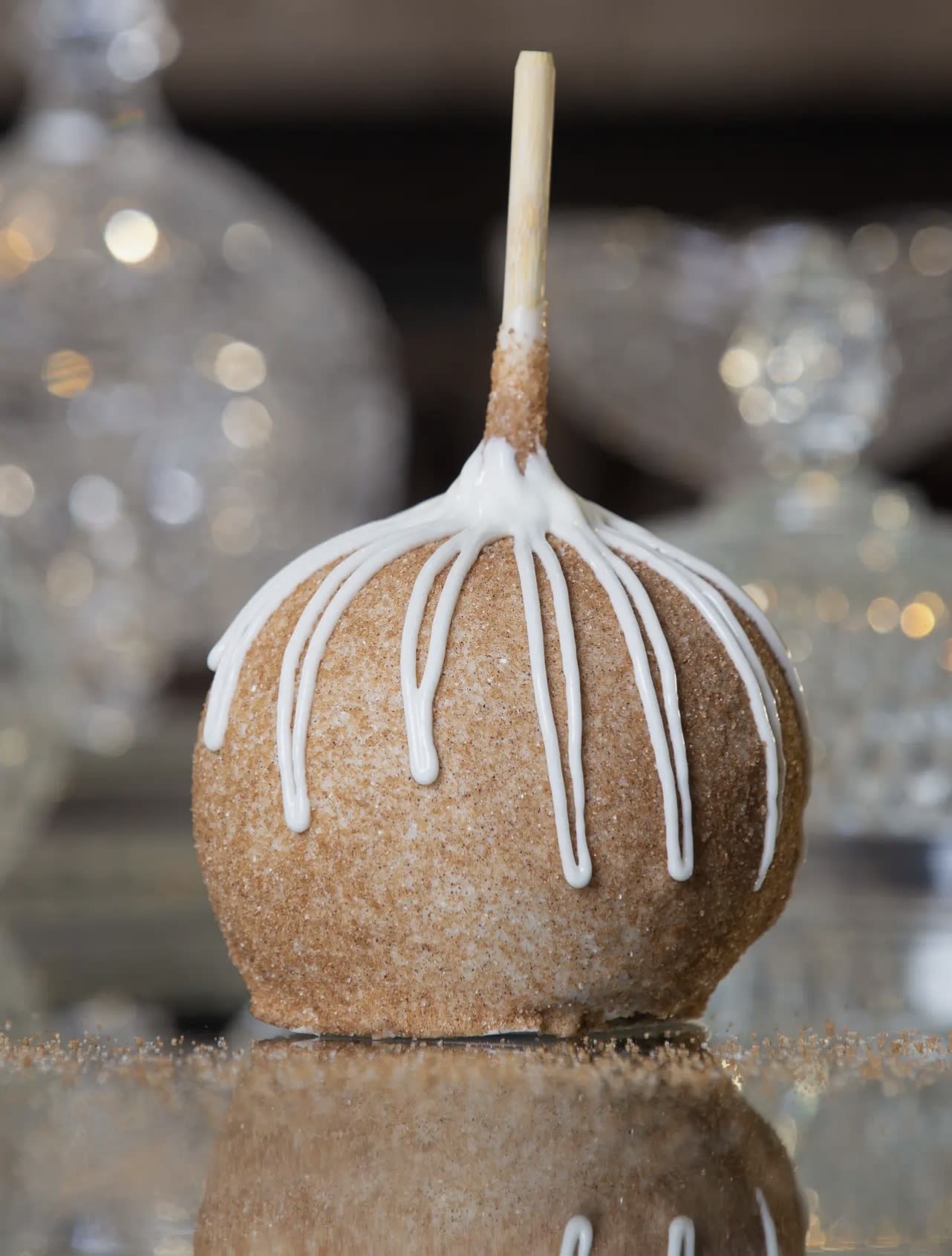 Caramel apple with white icing drizzle on a stick